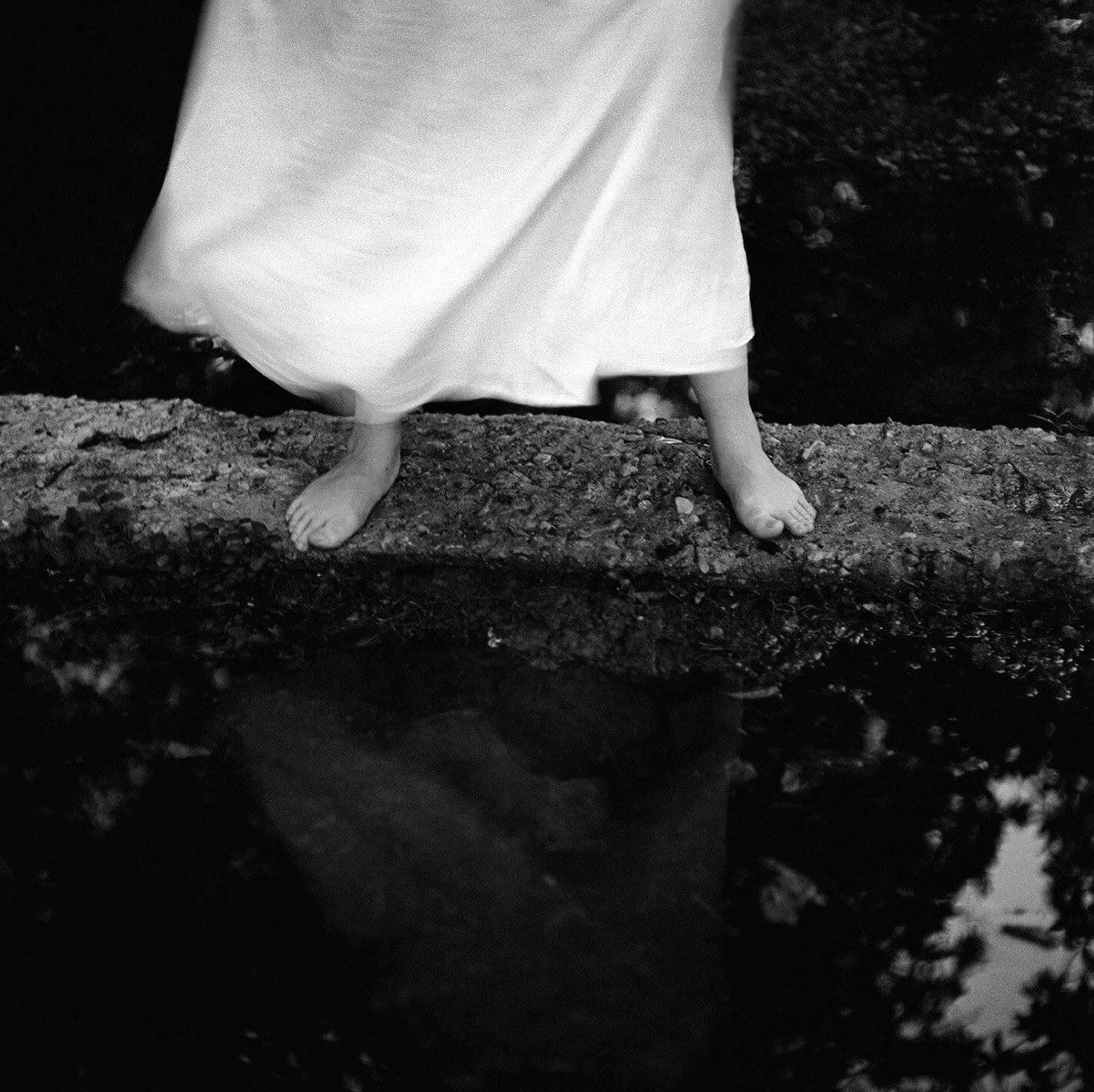 A woman's feet and blowing dress shot in black in white photography.