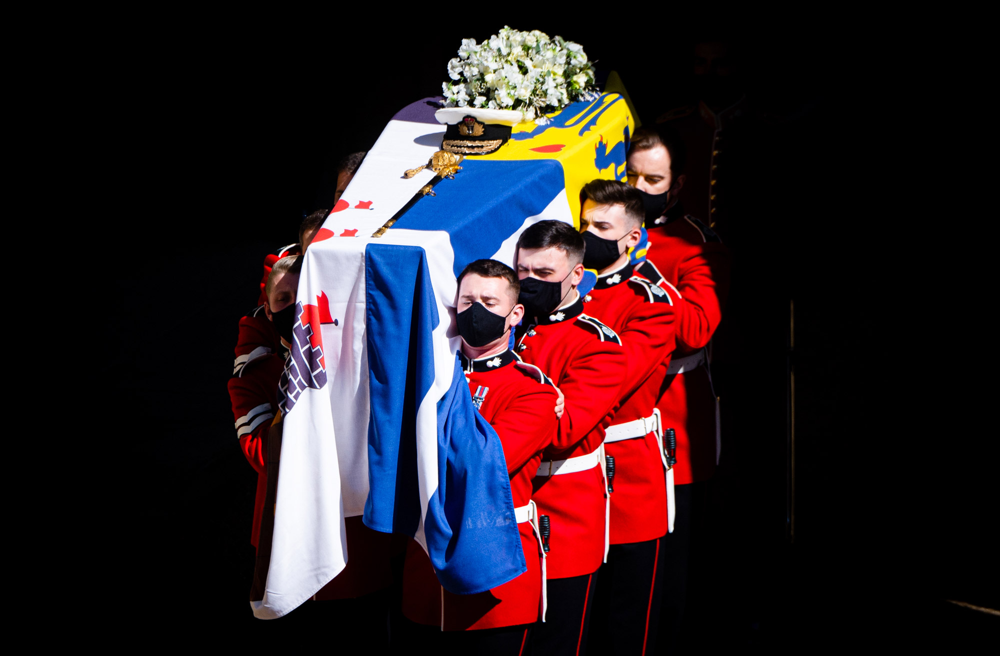 Four soldiers carry a coffin at the Duke of Edinburgh's funeral, there are flowers and a flag on top of the coffin.