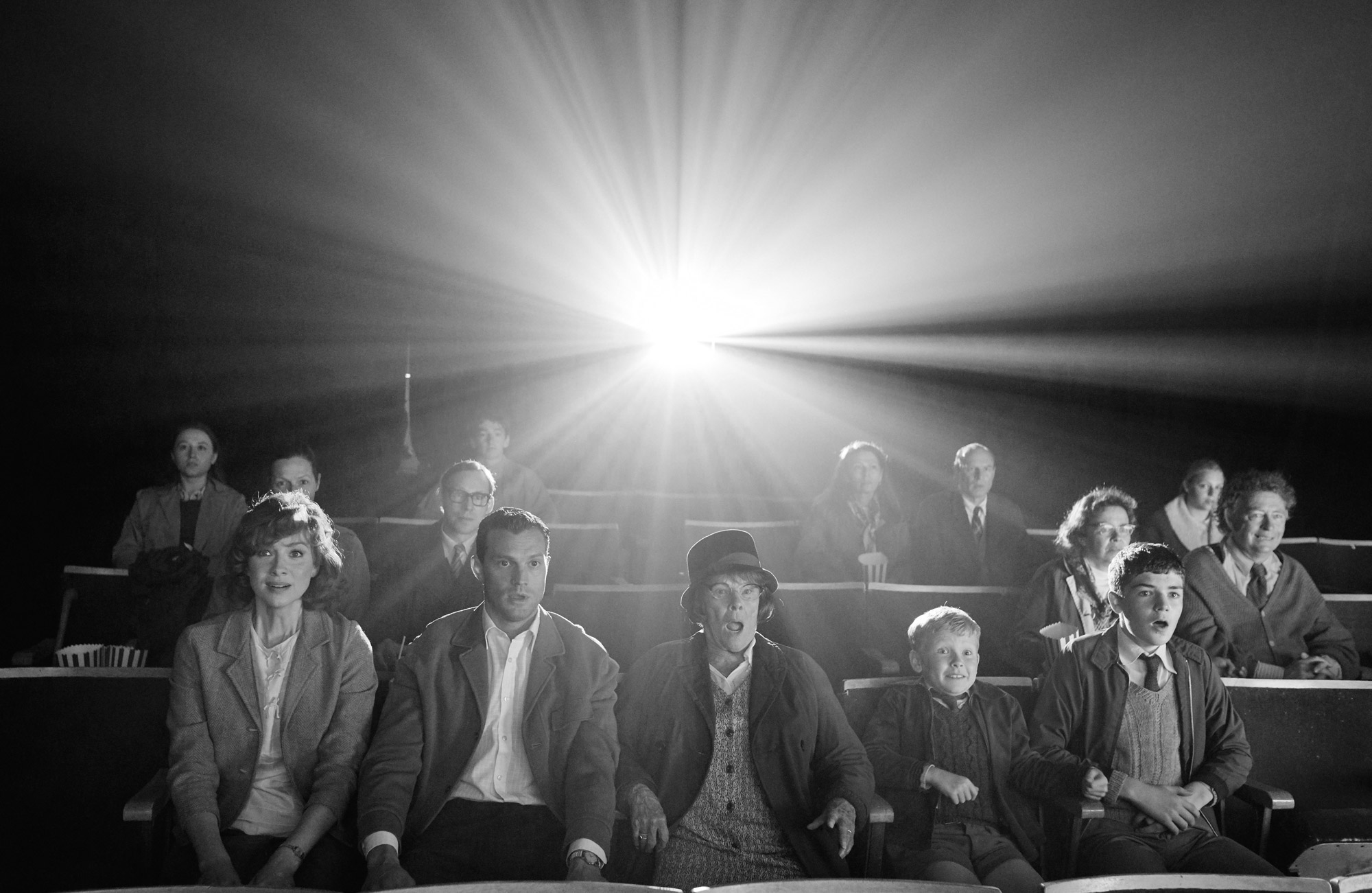 Five people look shocked in a cinema, with a bright light behind them.