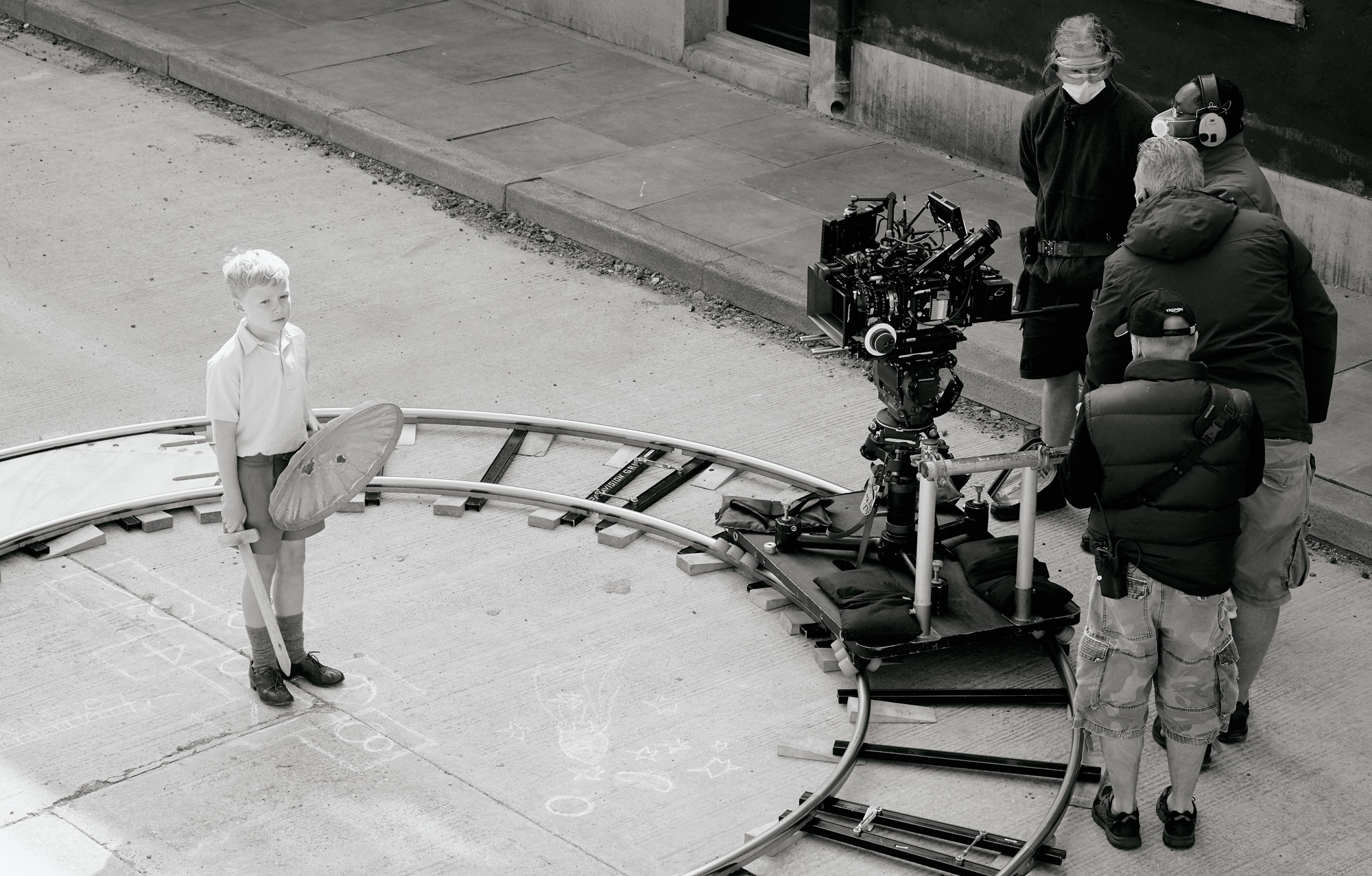 A camera on circular track points at a boy on the set of Belfast.