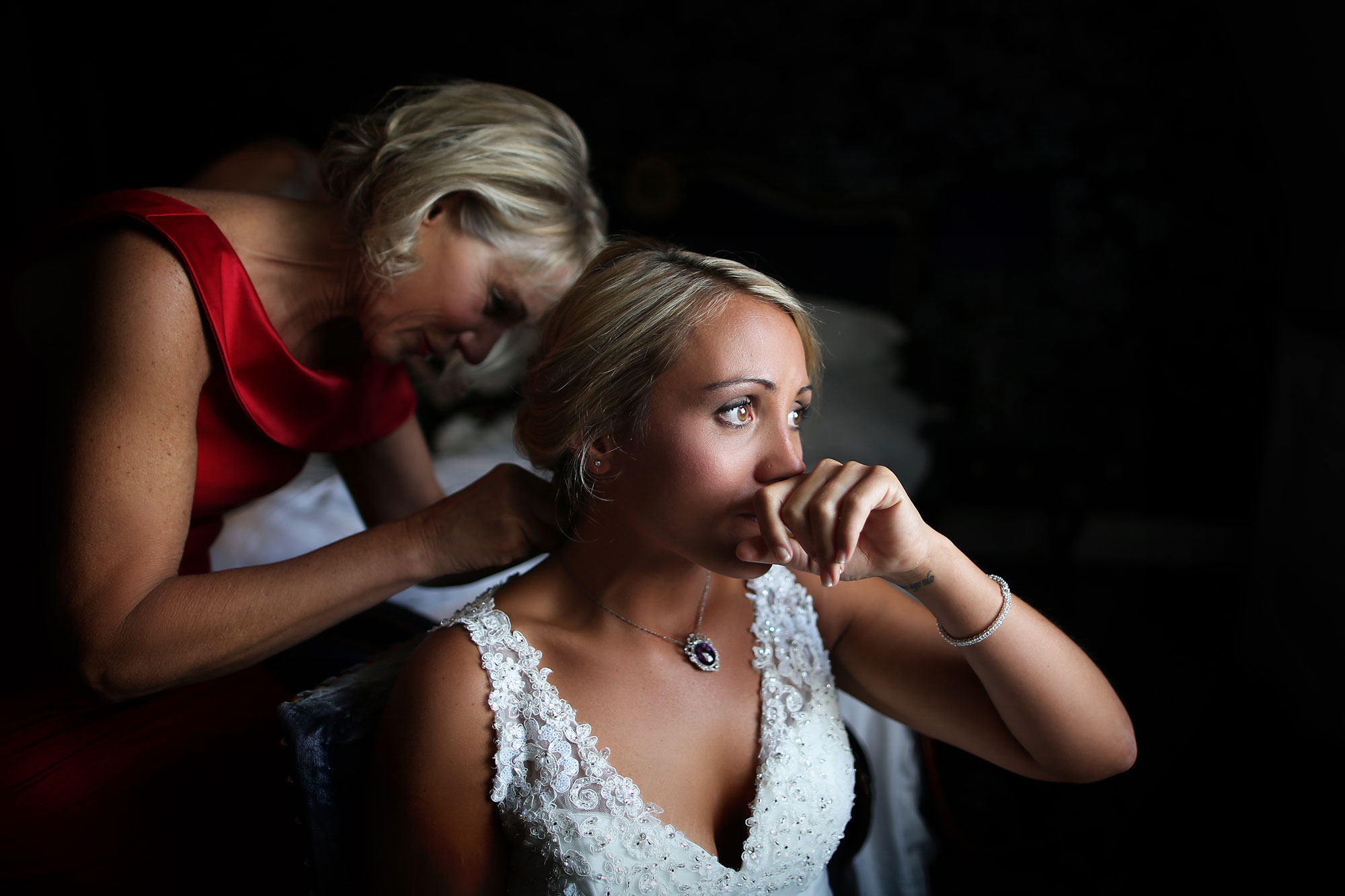 Nervous Bride looking the right while the mother is fixing her dress