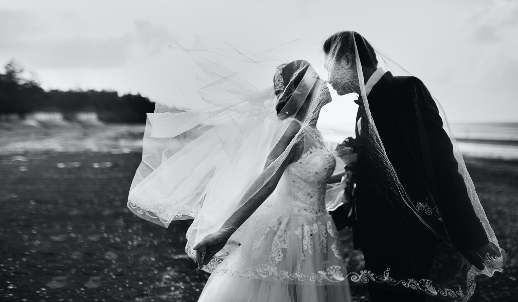 Photo en noir et blanc d'un couple en tenue de mariage s'embrassant