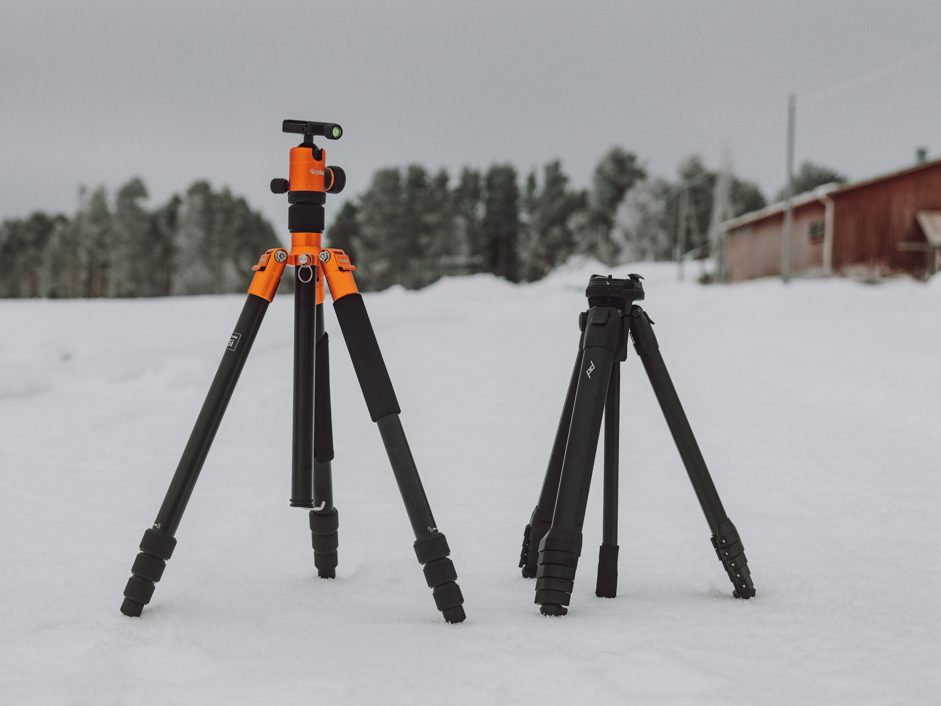 Photograph of two tripods set up side by side with a snowy background. 