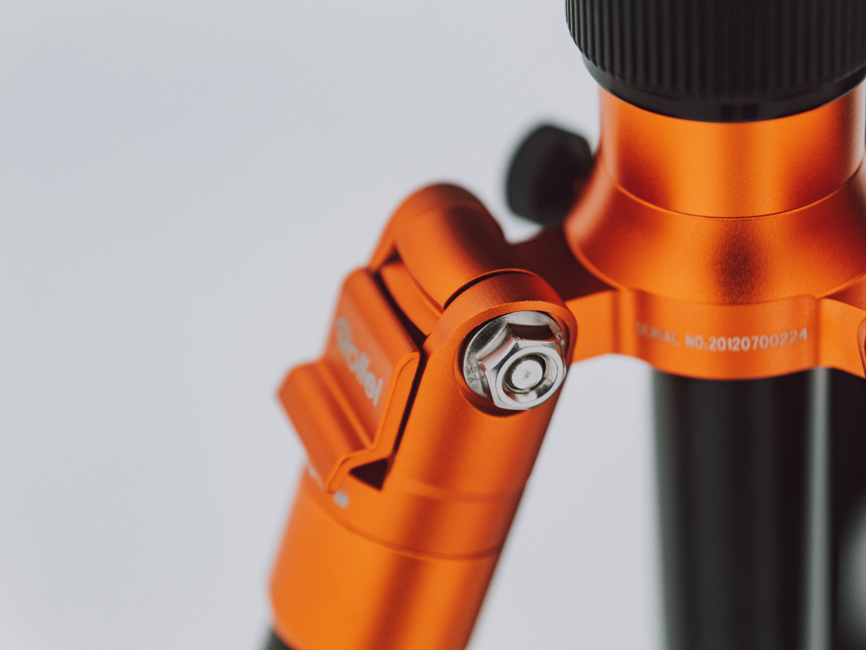 Close up photo of an orange and black tripod on a white background.