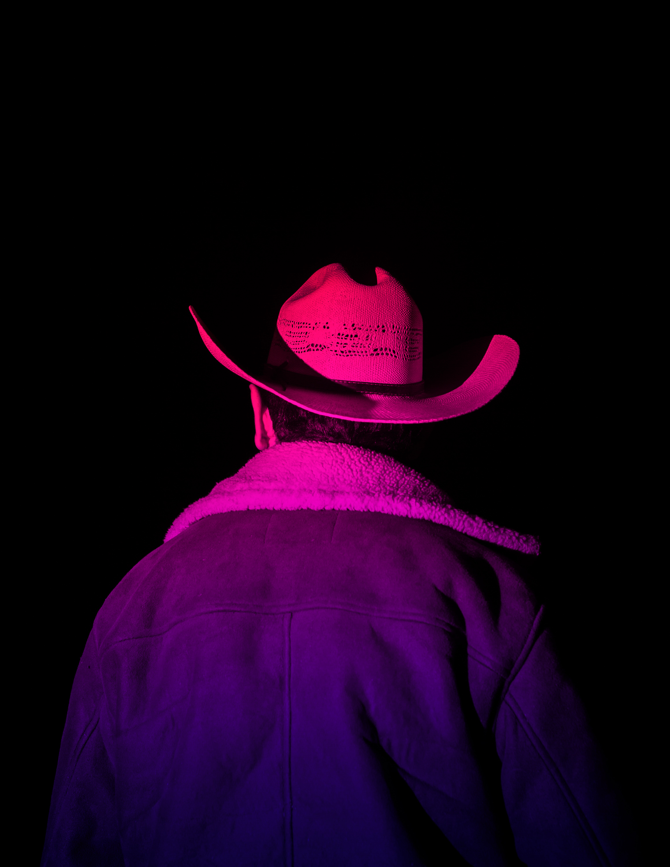 a cowboy shot from behind using red and purple artificial light