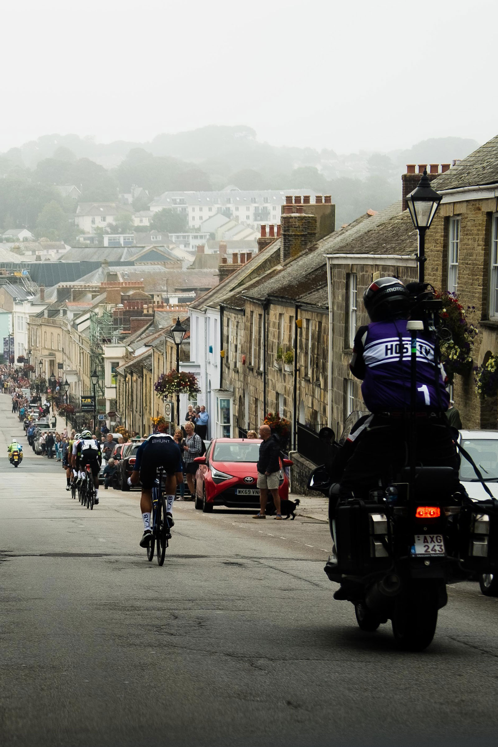 A photo of a UK town with motorcyclists and cyclists.
