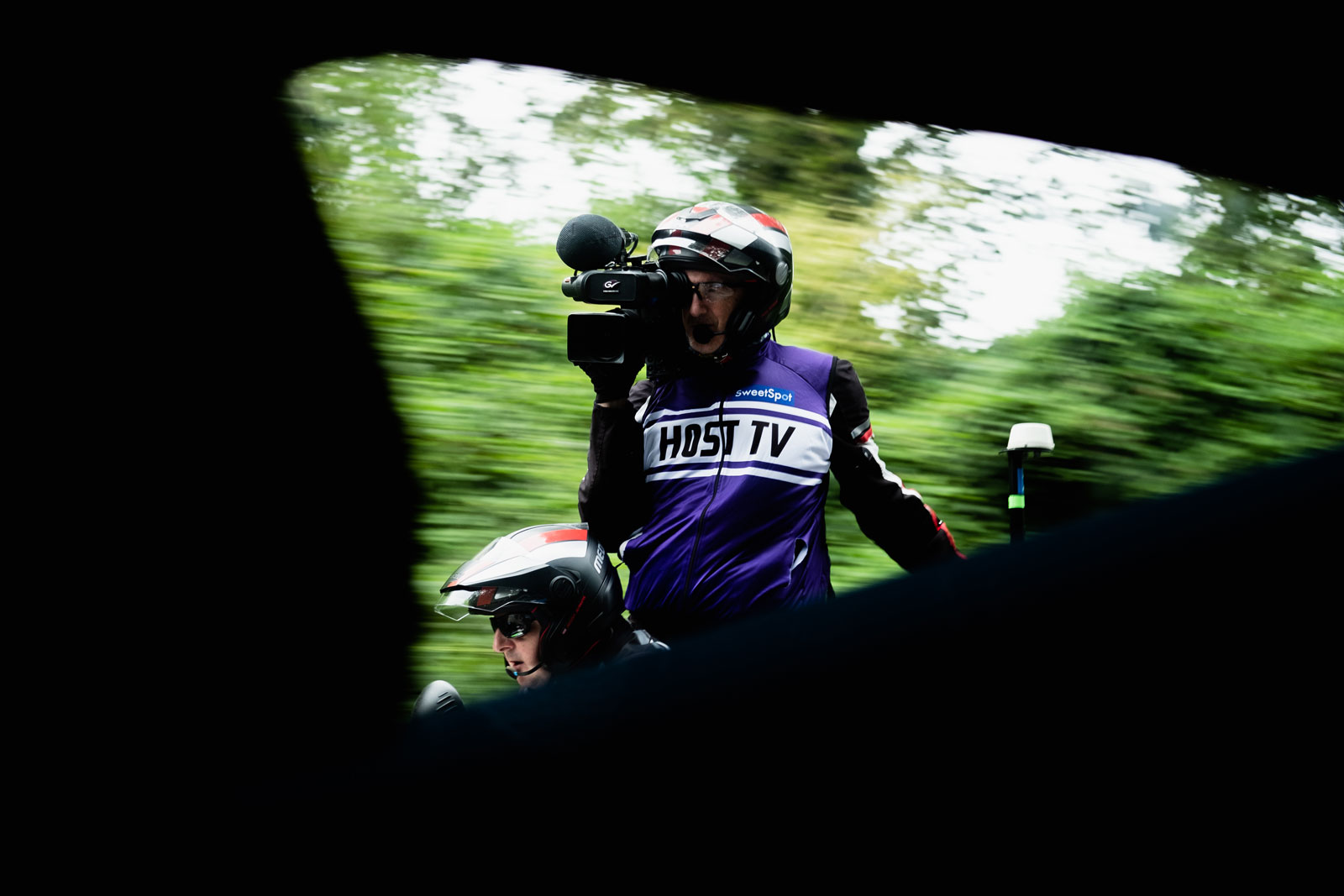 A man on a bicycle with a camera shot from the window of a car
