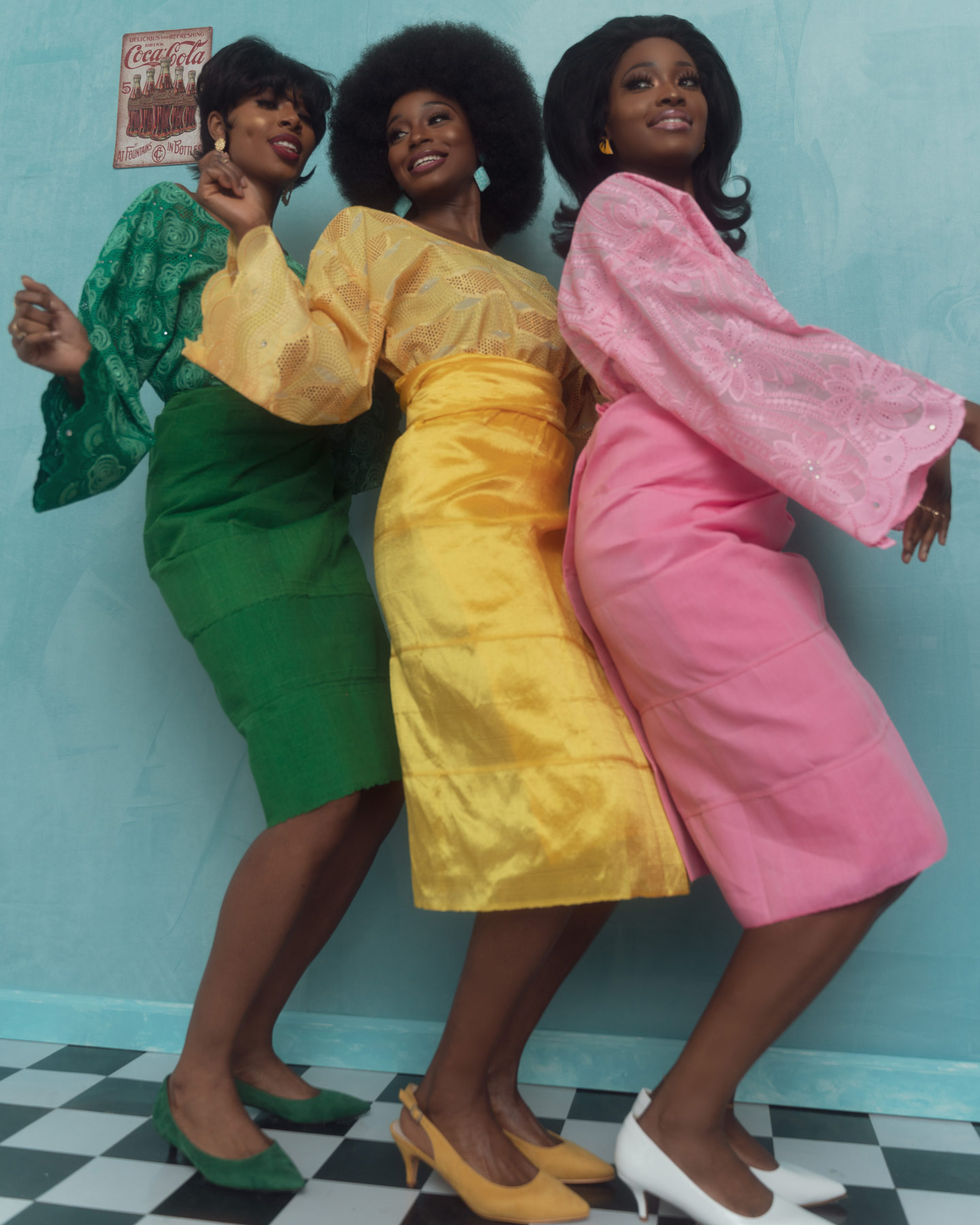 60s style group photo of three black women posing wearing a red yellow and pink dress respectively