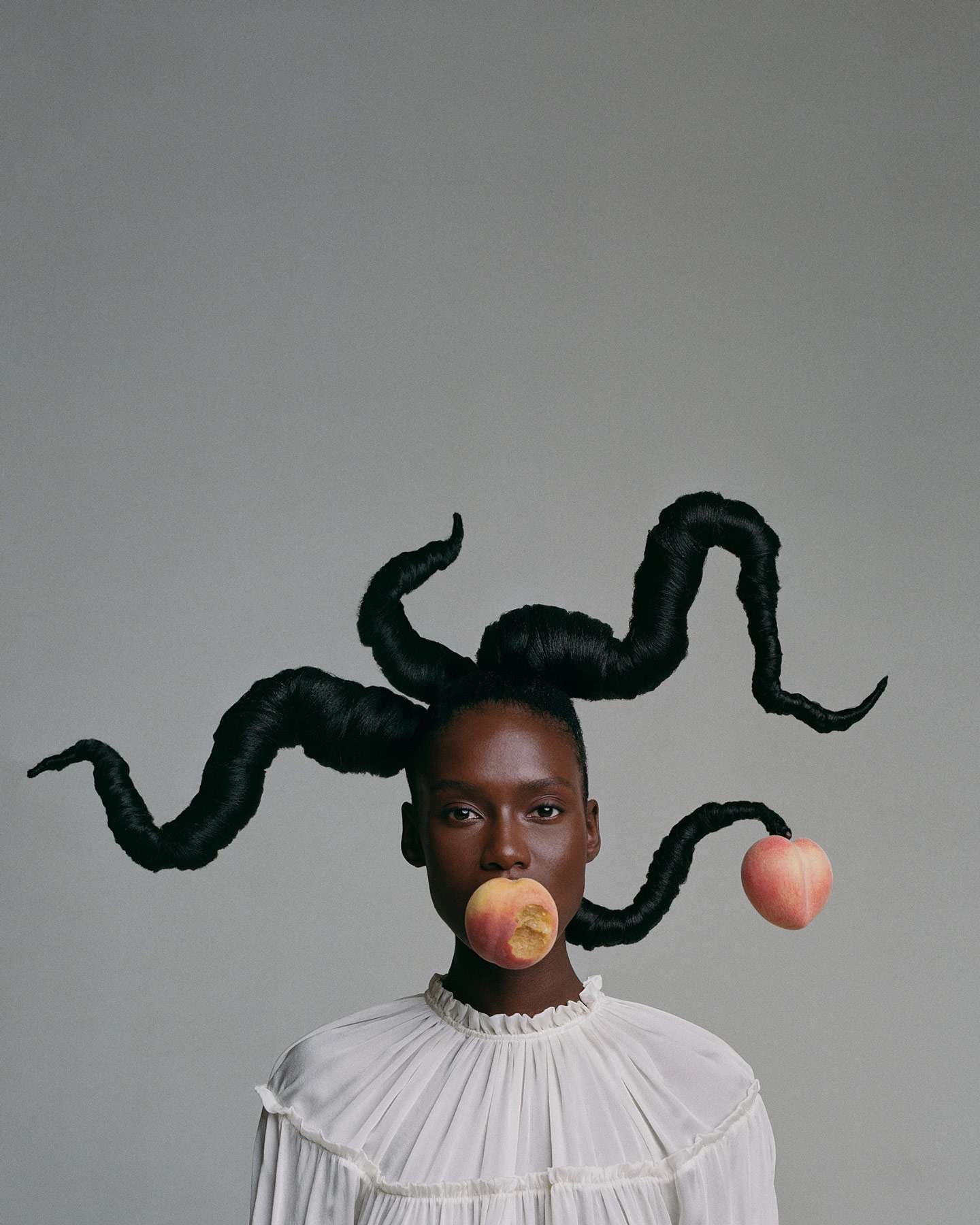 A portrait of a black woman with a peach in their mouth their hair is styled to resemble the branches of a tree with a single peach hanging from one of the branches