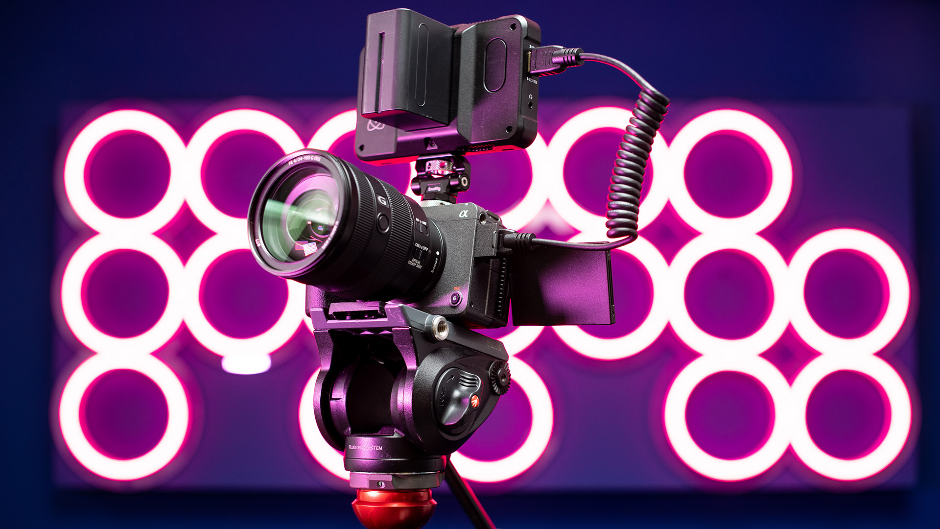 Eine Sony FX3 auf einem Videostativ mit einem Atomos-Monitor vor einem neonpinken MPB-Logo.

