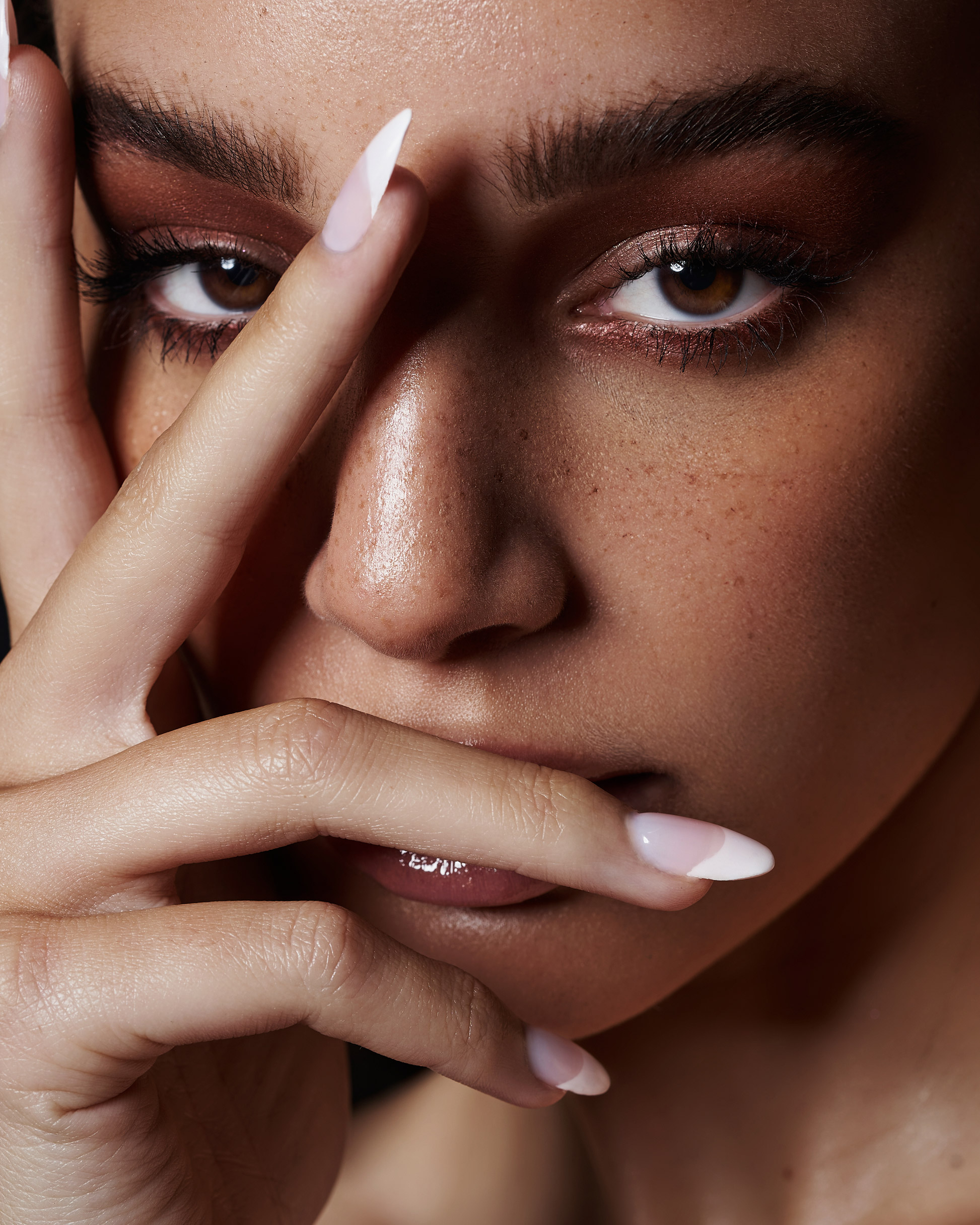 A close up of a model, Charletta Jones, covering their face with their hands, with makeup by Natalia Garcia