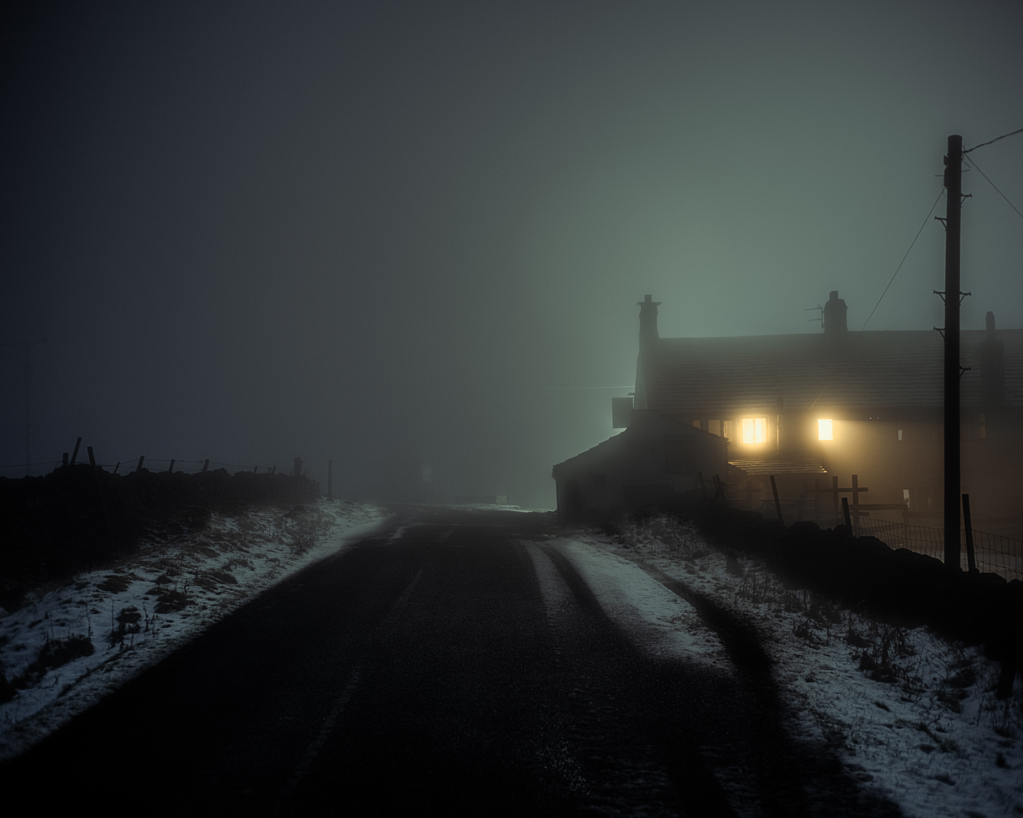 A foggy nighttime winter scene with a single light emanating from a window, shot with 1/4 Tiffen Pro Mist softening filter