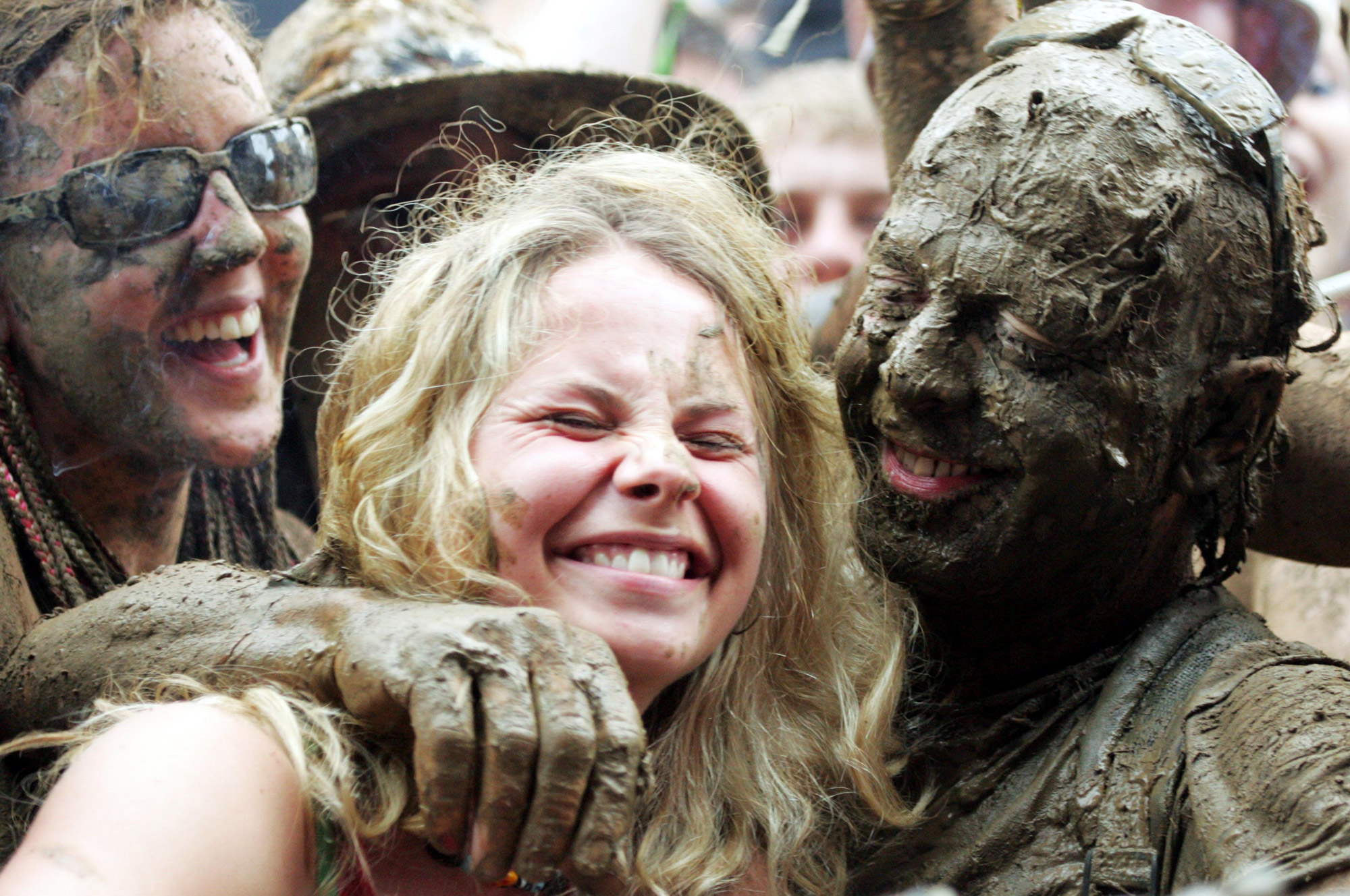 A festival-goer is hugged by a person covered in mud at Glastonbury Festival 2005