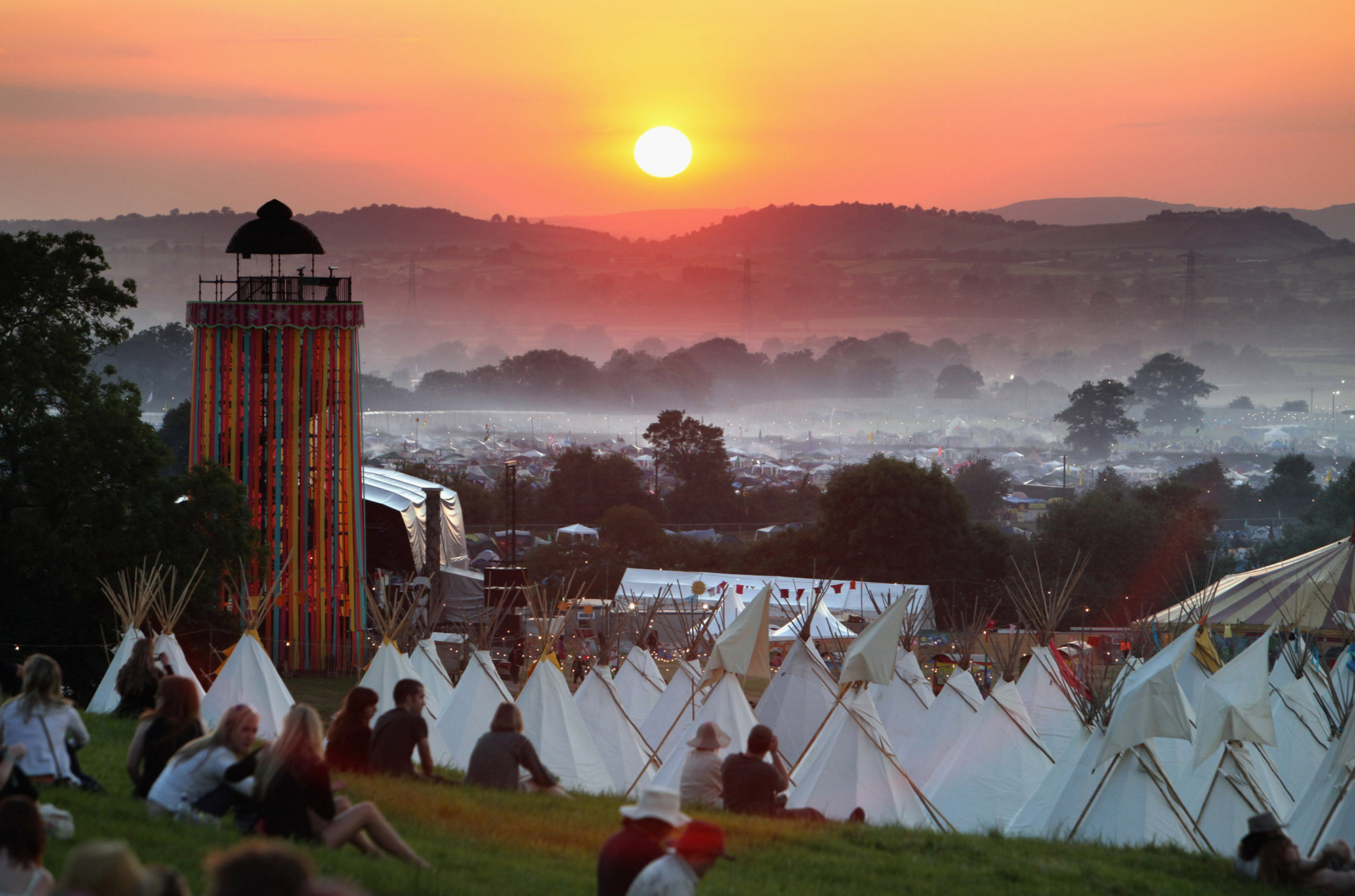 People gather to watch the sunset on a hill above the tipi field as music fans start to arrive at the Glastonbury Festival site at Worthy Farm, Pilton on June 24, 2009.