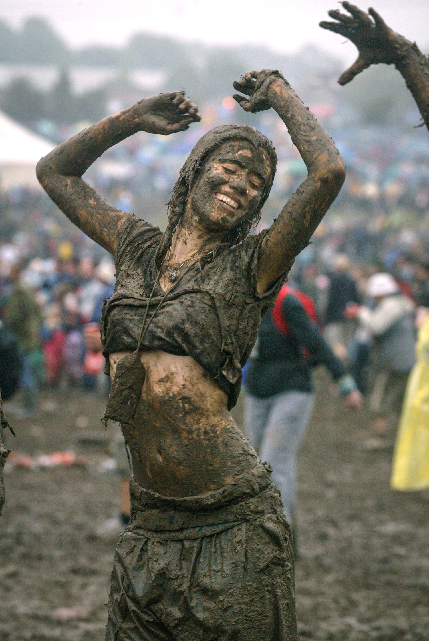 Festival revellers dance in the mud in front of the Pyramid Stage at the 2004 Glastonbury Festival held at Worthy Farm in Pilton, Somerset on June 26, 2004.