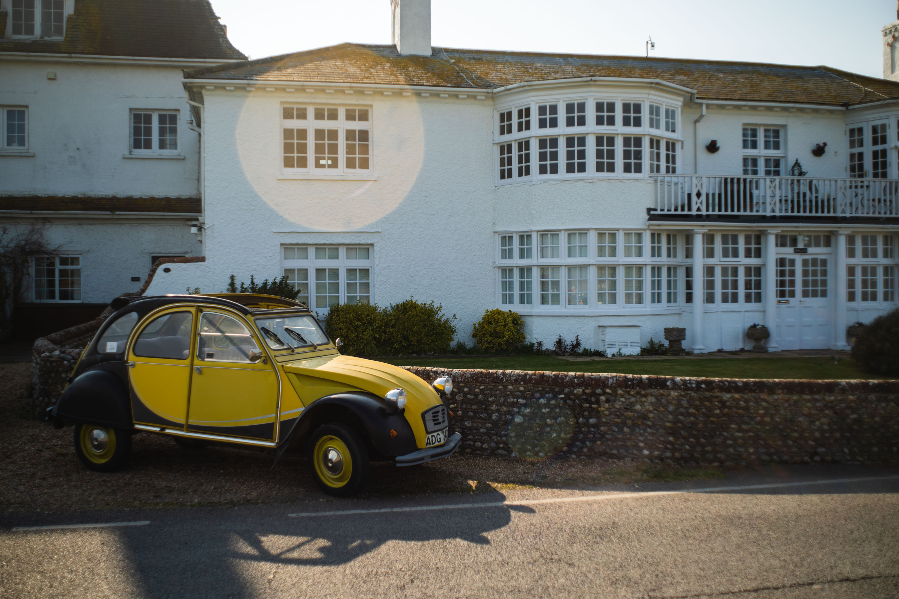 A photo of a yellow Citroen in the high morning sun with lens flare