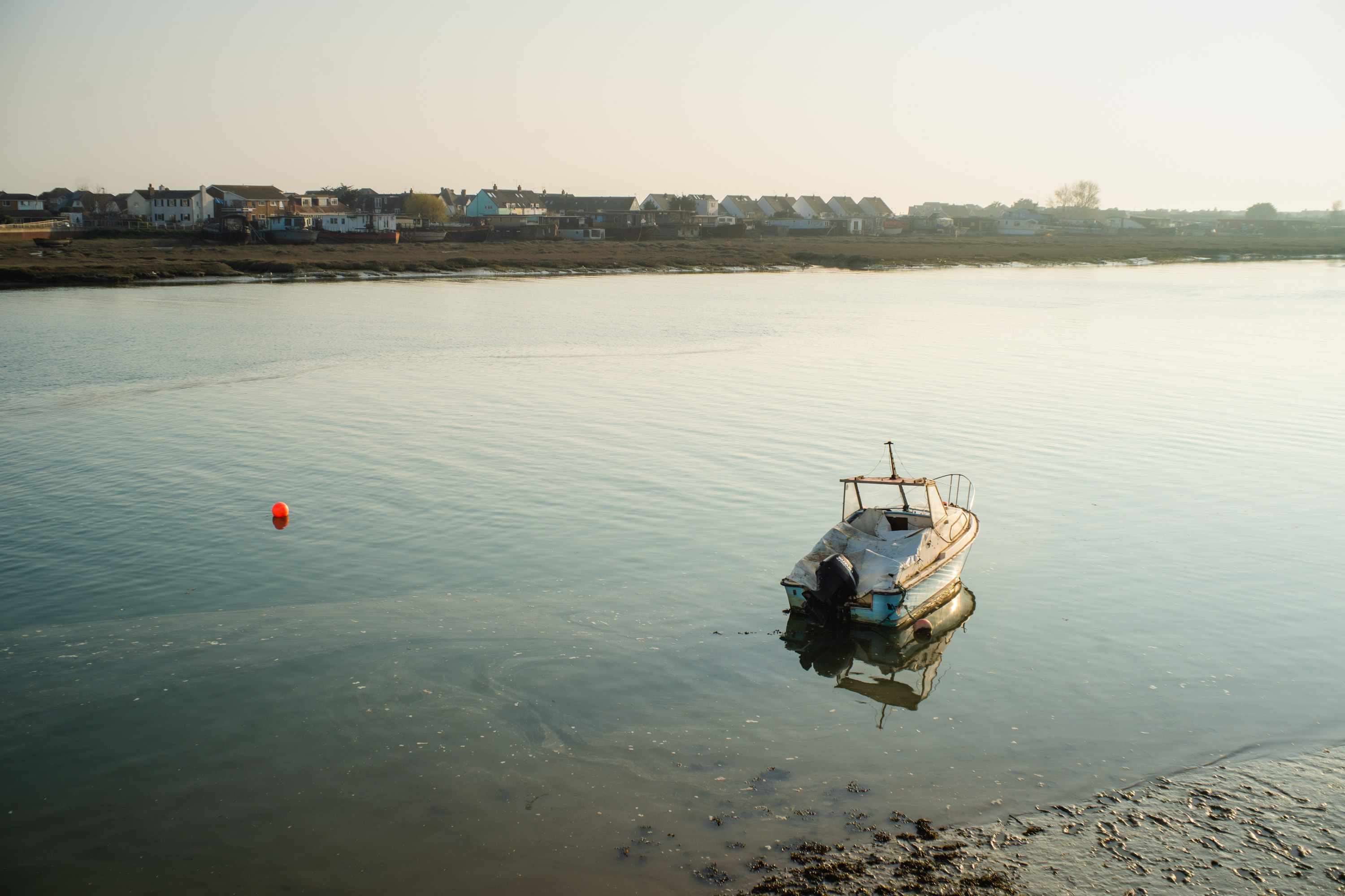 A picture of a boat in a river in the evening without lens flare