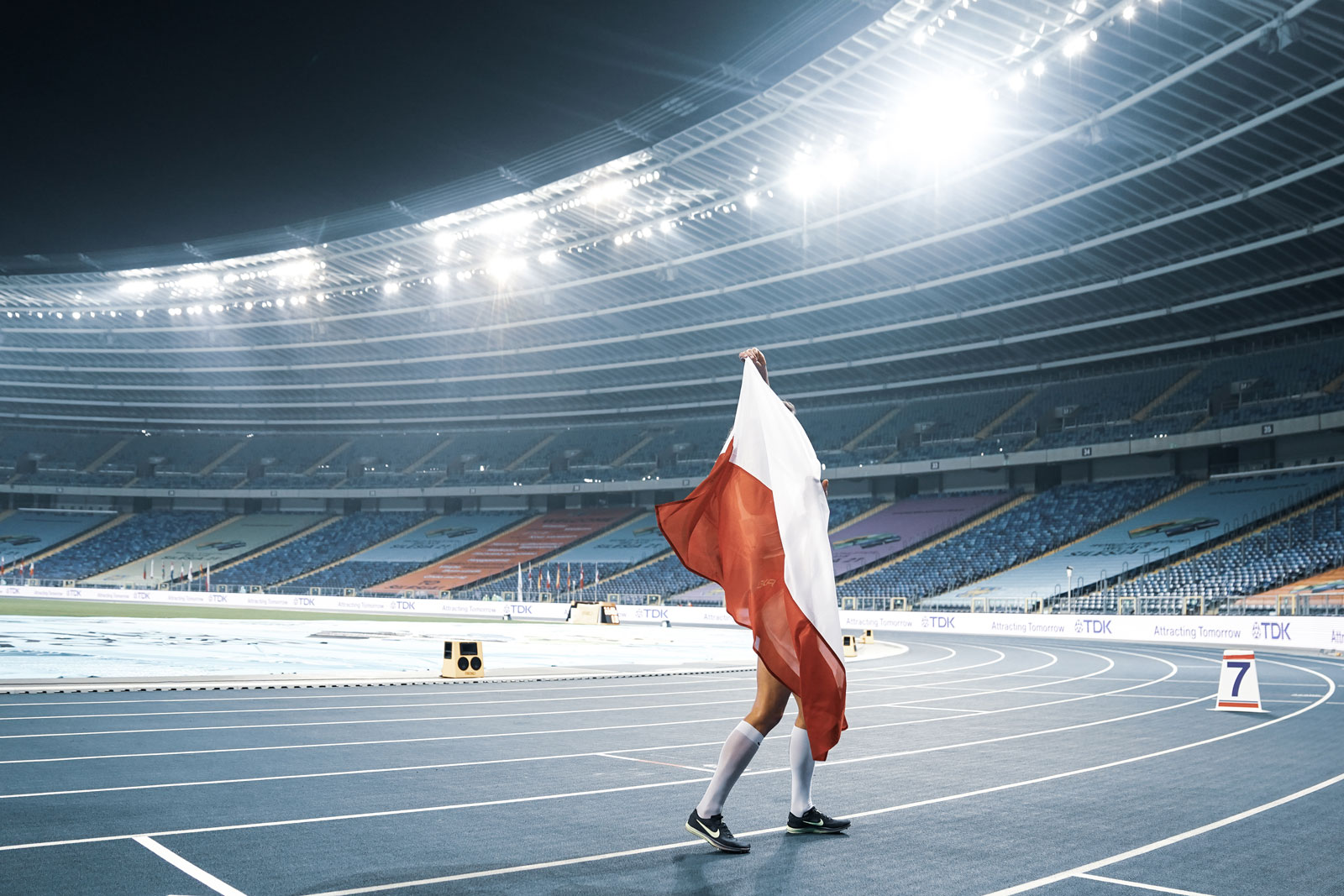 Foto van Poolse atleet die de vlag vasthoudt in een stadion.