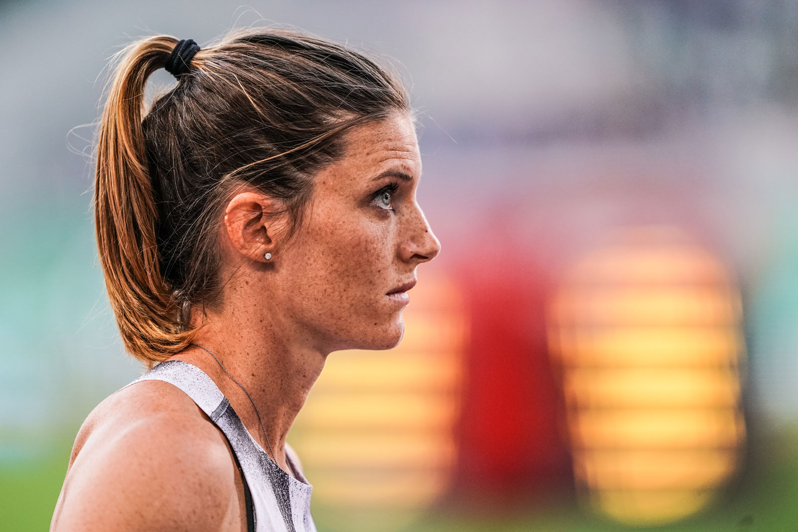 Foto van een atleet die geconcentreerd kijkt met een wazige kleurrijke achtergrond.