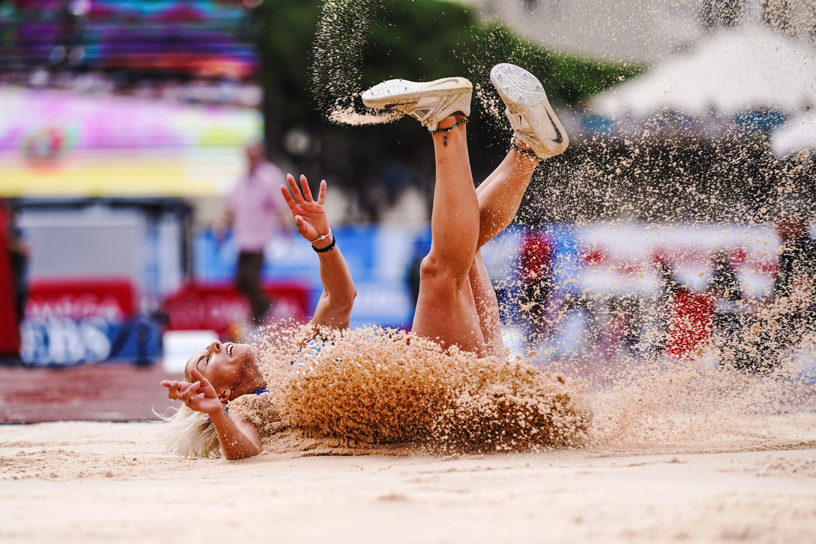 Foto einer Weitspringerin, die in den Sand fällt.