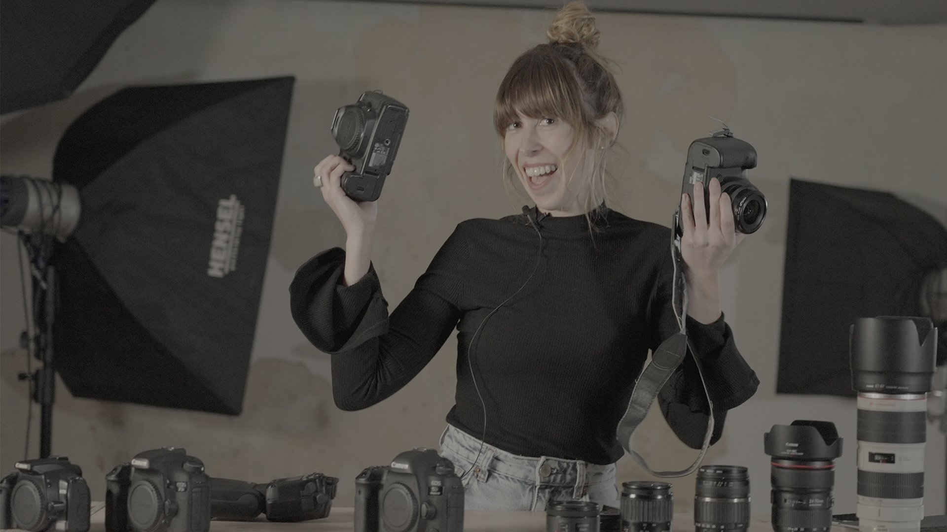 Een vrouw lacht in de camera terwijl ze twee Canon camera's vasthoudt.