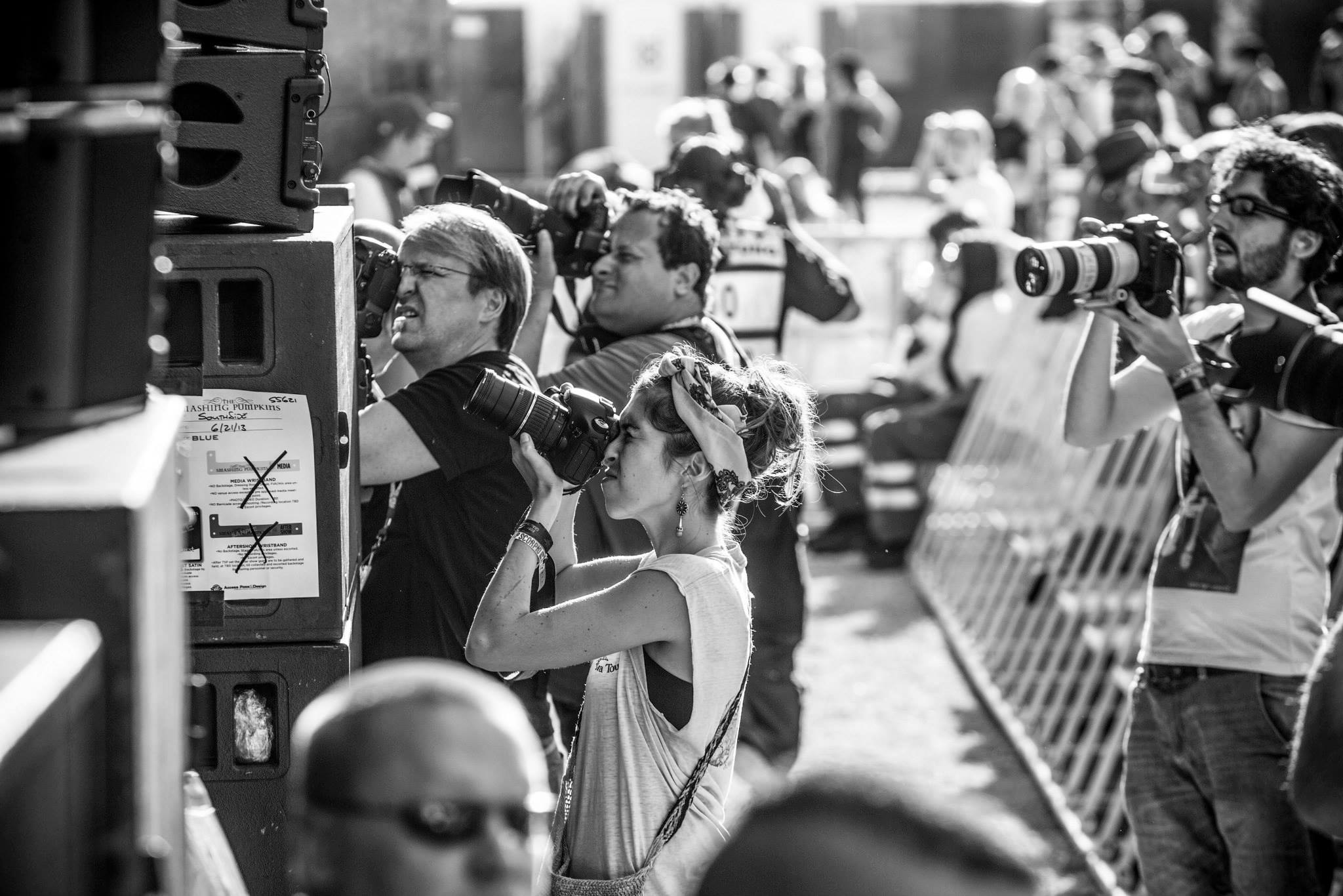A woman standing in a crowd while she is photographing a music festival.