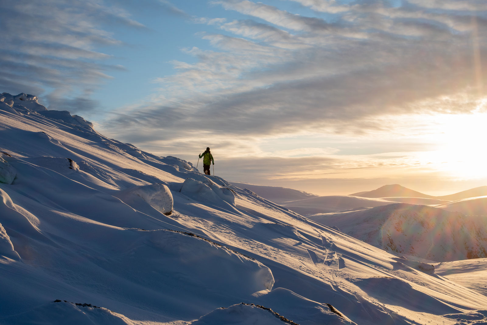 Snowboarder au loin sur une pente au coucher du soleil