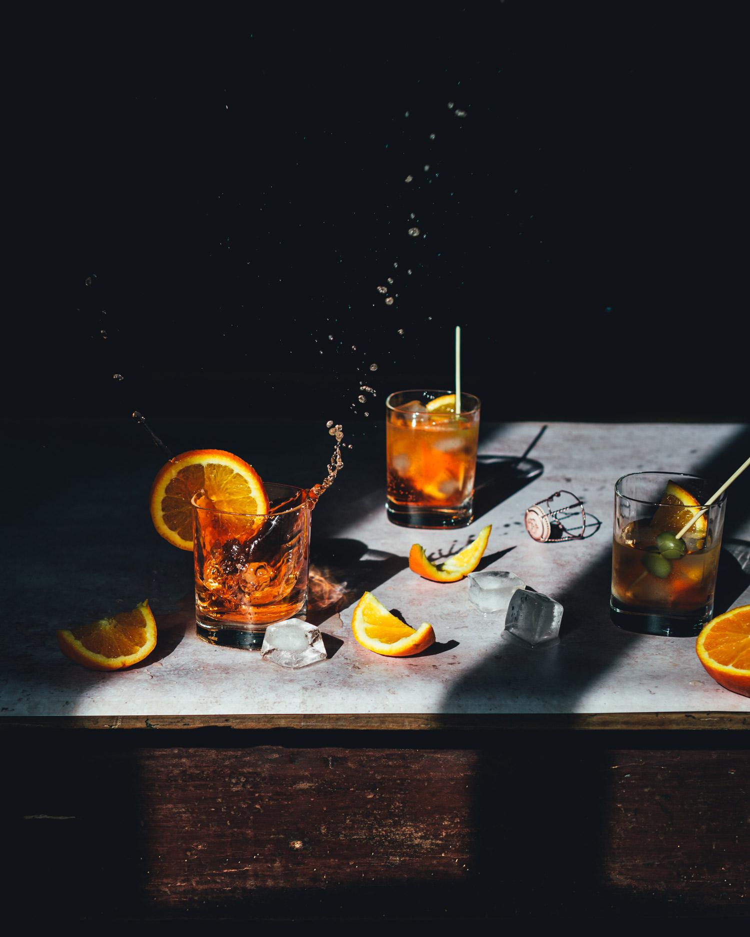A table full of blood oranges, some cut in half or segments, with five hands chopping and holding them.