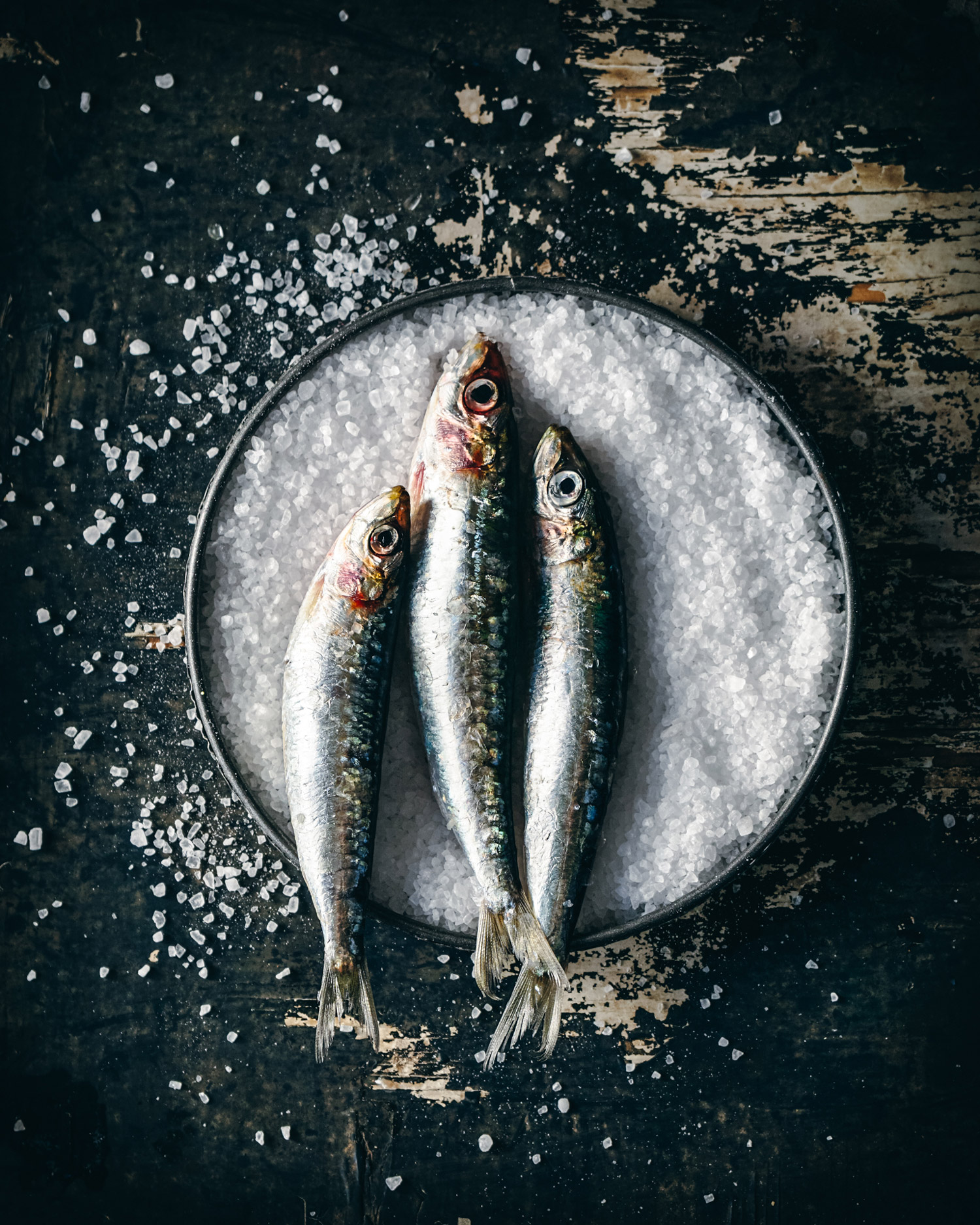 Three fish on a dish filled with salt crystals.