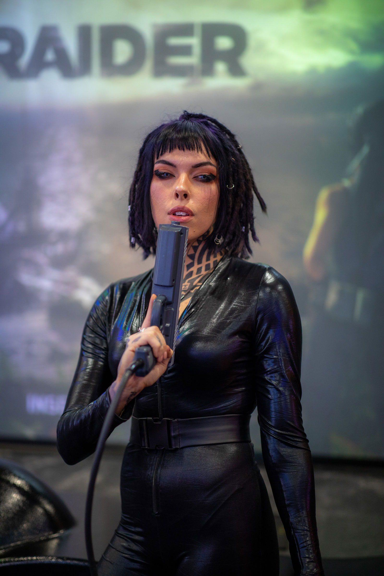 Model with dark hair wearing leather holding an arcade gun. Image created with Canon EOS 5D Mark IV + Canon 85mm f/1.4 L IS