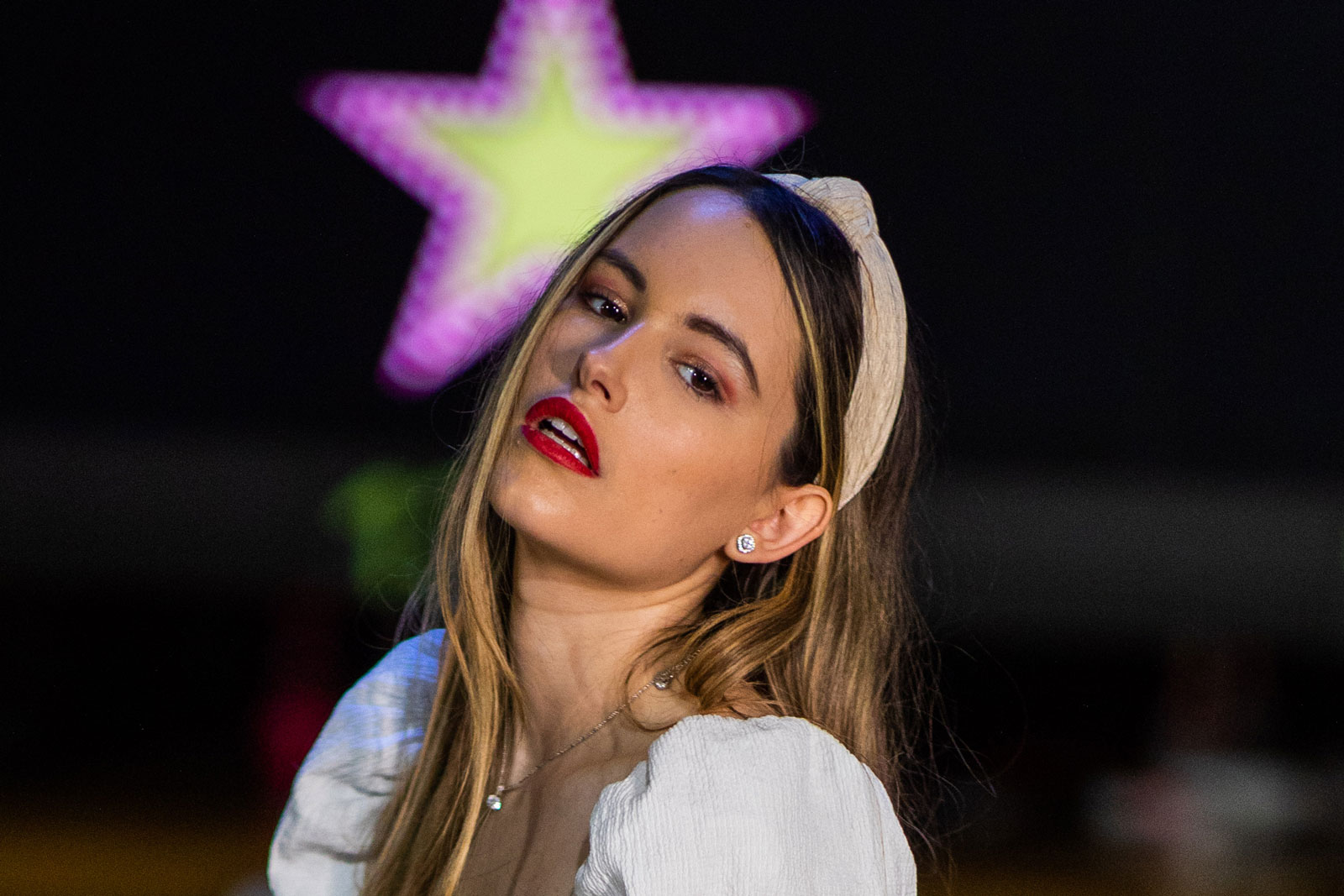 100% crop to demonstrate softness and sharpness of the Canon EF 85mm f/1.4 L IS. A model wearing orange trousers and a white top stands holding a bowling ball in a bowling alley. Shot with Canon EOS 5D Mark IV + Canon EF 85mm f/1.4 L IS.