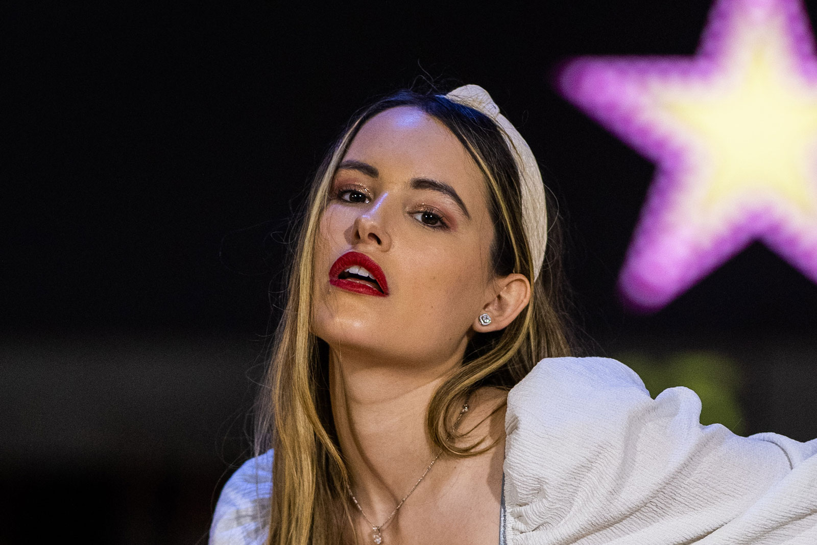 100% crop to demonstrate softness and sharpness of the Canon RF 85mm f/1.2 L. A model wearing orange trousers and a white top stands holding a bowling ball in a bowling alley. Shot with Canon EOS R5 + Canon RF 85mm f/1.2 L
