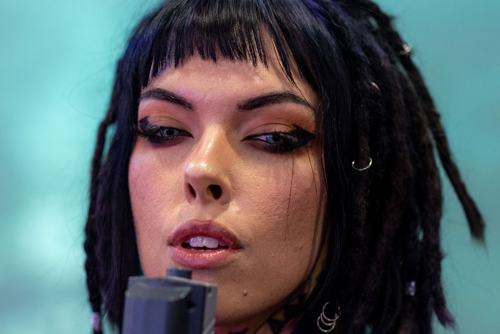 A 100% crop to demonstrate sharpness of the Canon RF 85mm f/1.2 L. Model with dark hair wearing leather holding an arcade gun. Image created Canon EOS R5 + Canon RF 85mm f/1.2 L