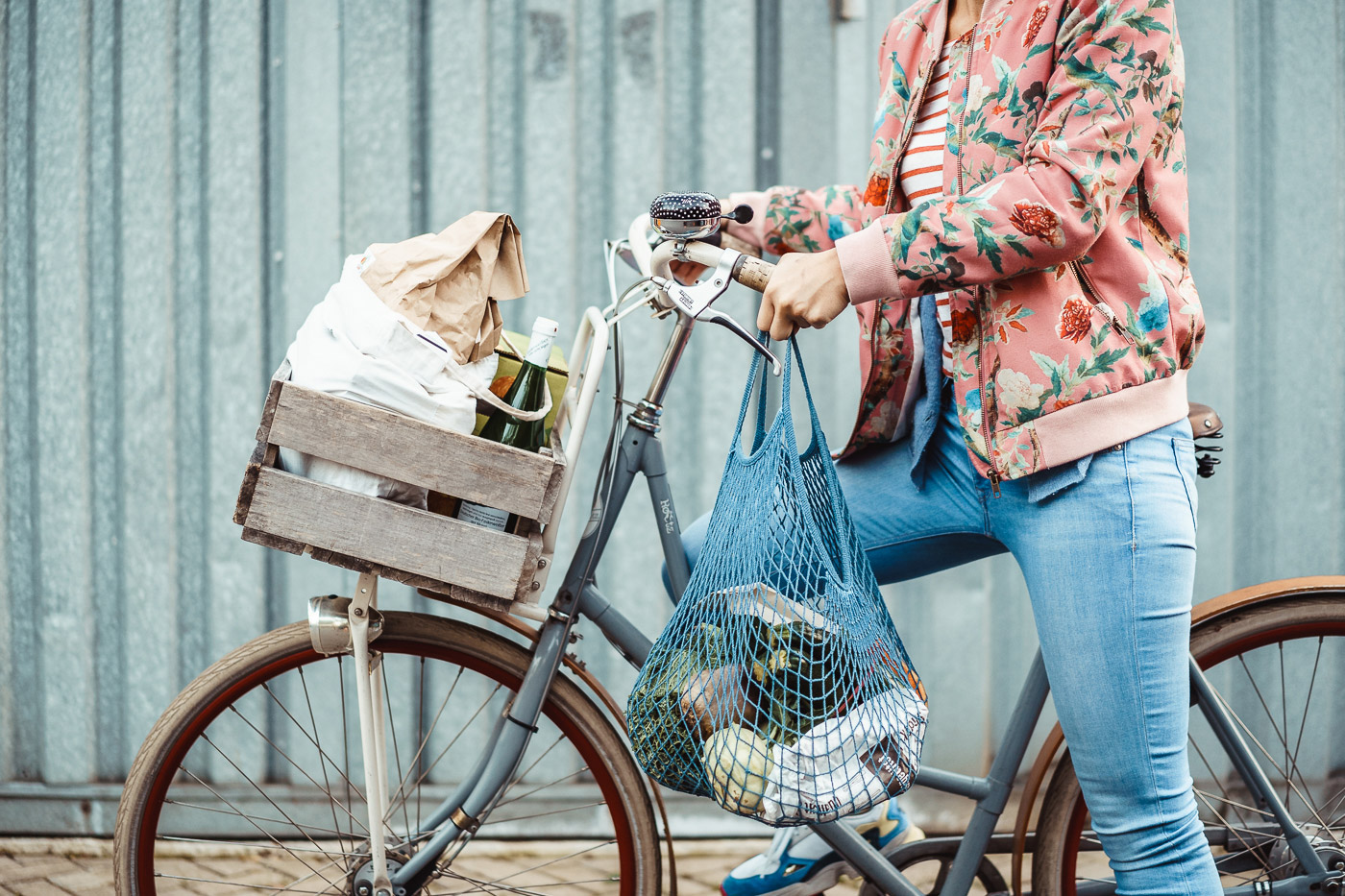A person on a bicycle with a bag of goods.