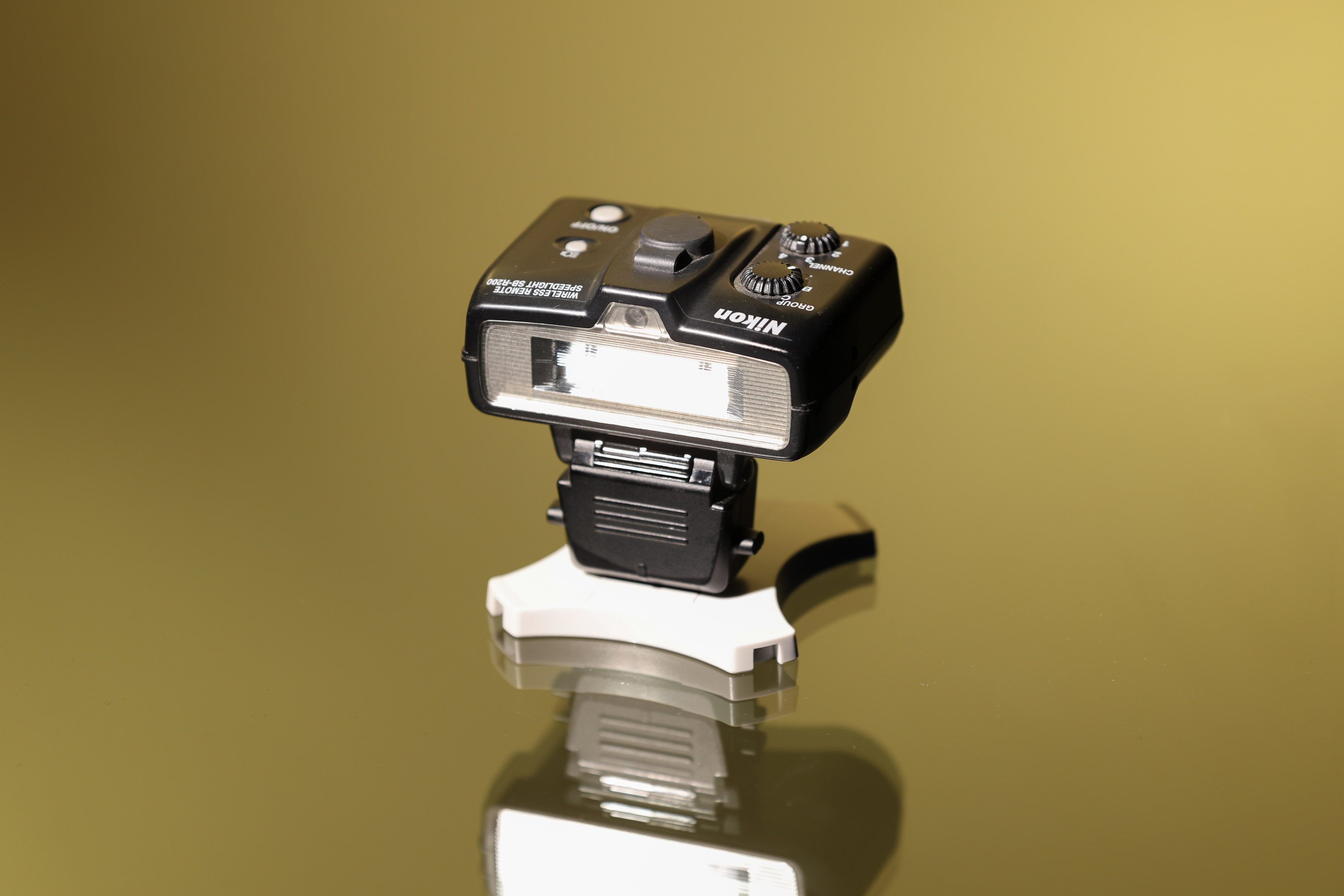 Nikon SB-R200 Speedlight against a gold background.