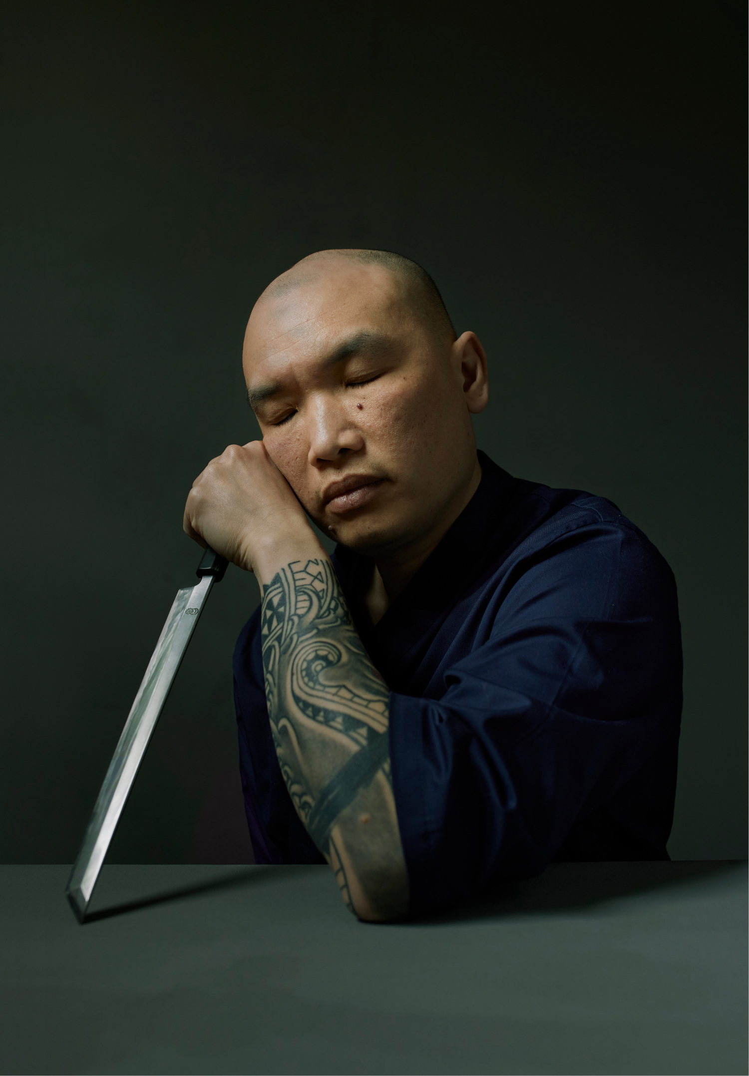 Sushi Chef, leaning on a long knife, with their sleeves rolled up and a tattoo on display
Second Prize, MPB Scottish Portrait Award in Photography 2023