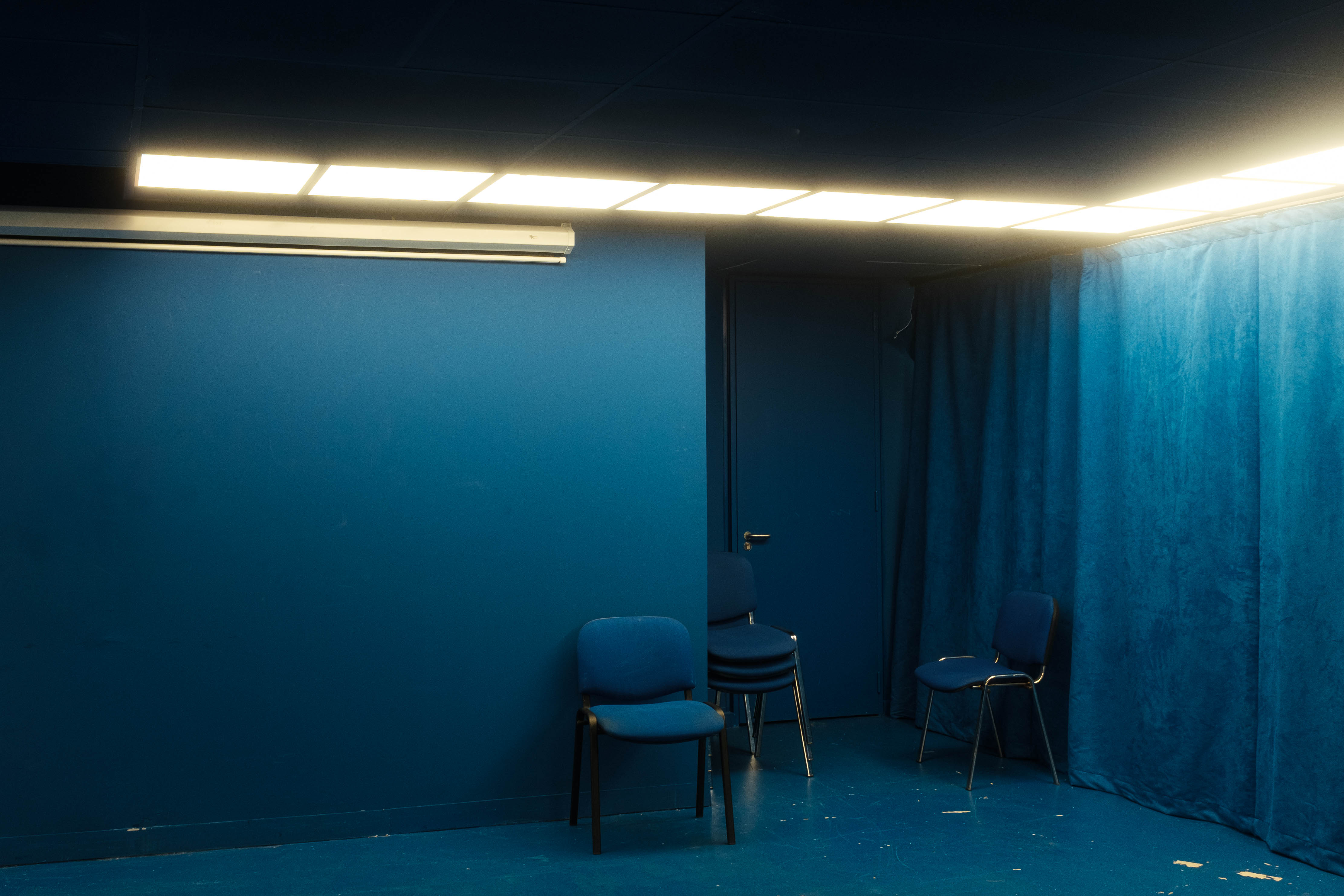 Bild eines blauen Zimmers mit blauen Stühlen und blauen Vorhängen. Aufgenommen von Connor Redmond mit einer Fujifilm X100F.