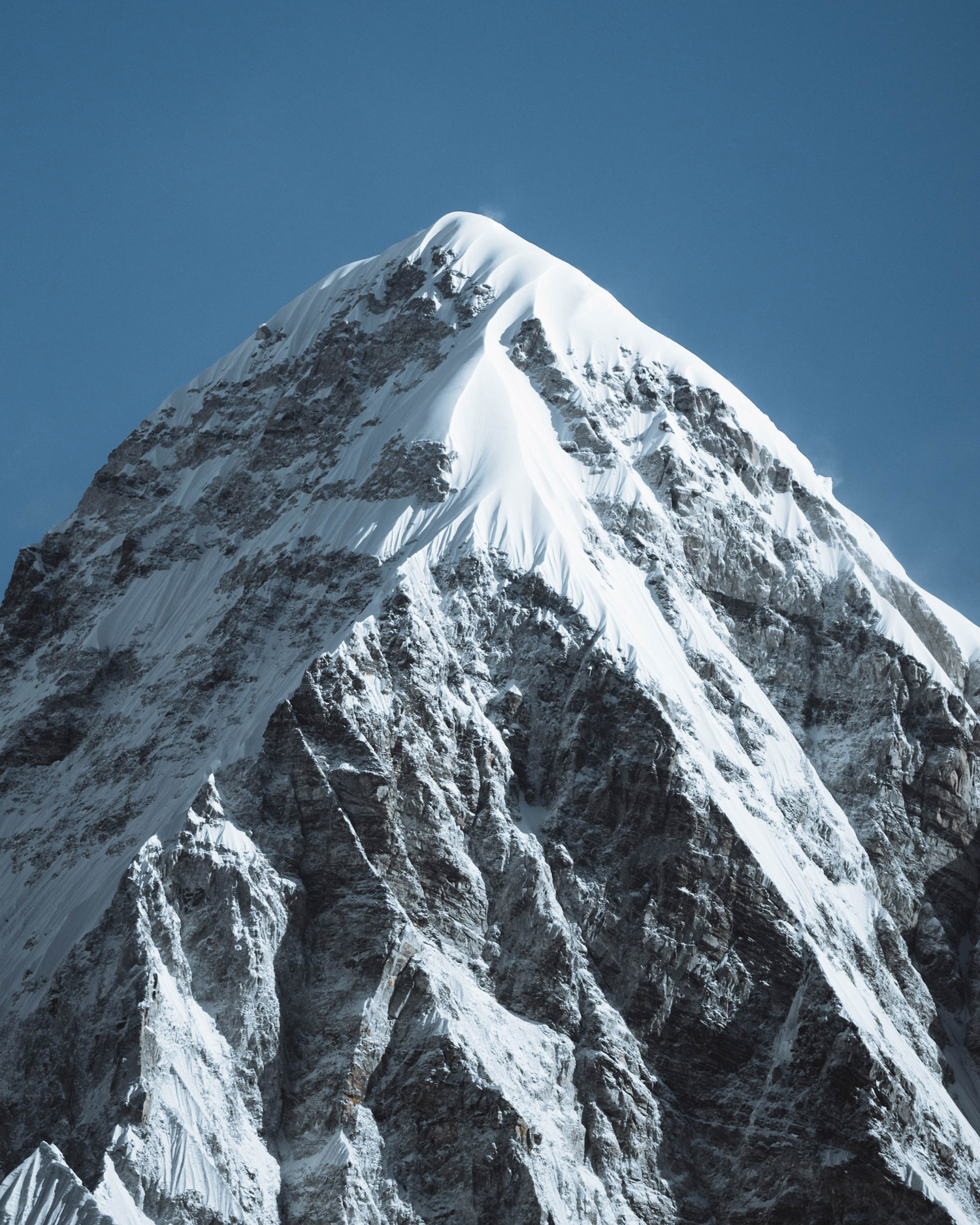 A snowy mountain peak with blue sky in the background, shot by Jack Anstey with the Sony Alpha A7 IV and the Sony FE 70-200mm f/4 G OSS.