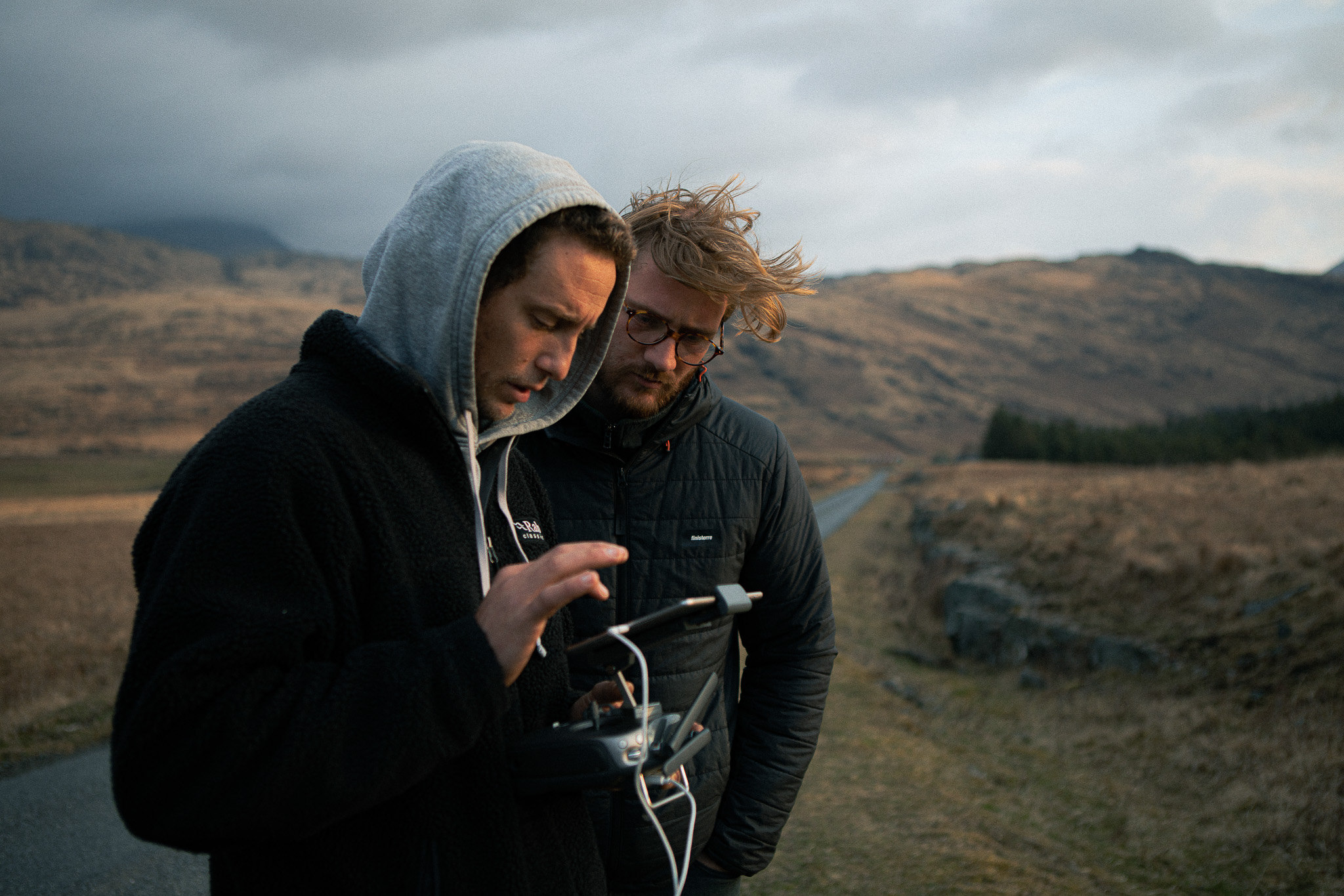 Deux personnes regardant l'écran de contrôle d'un drone tout en se trouvant dans un paysage brun pittoresque.