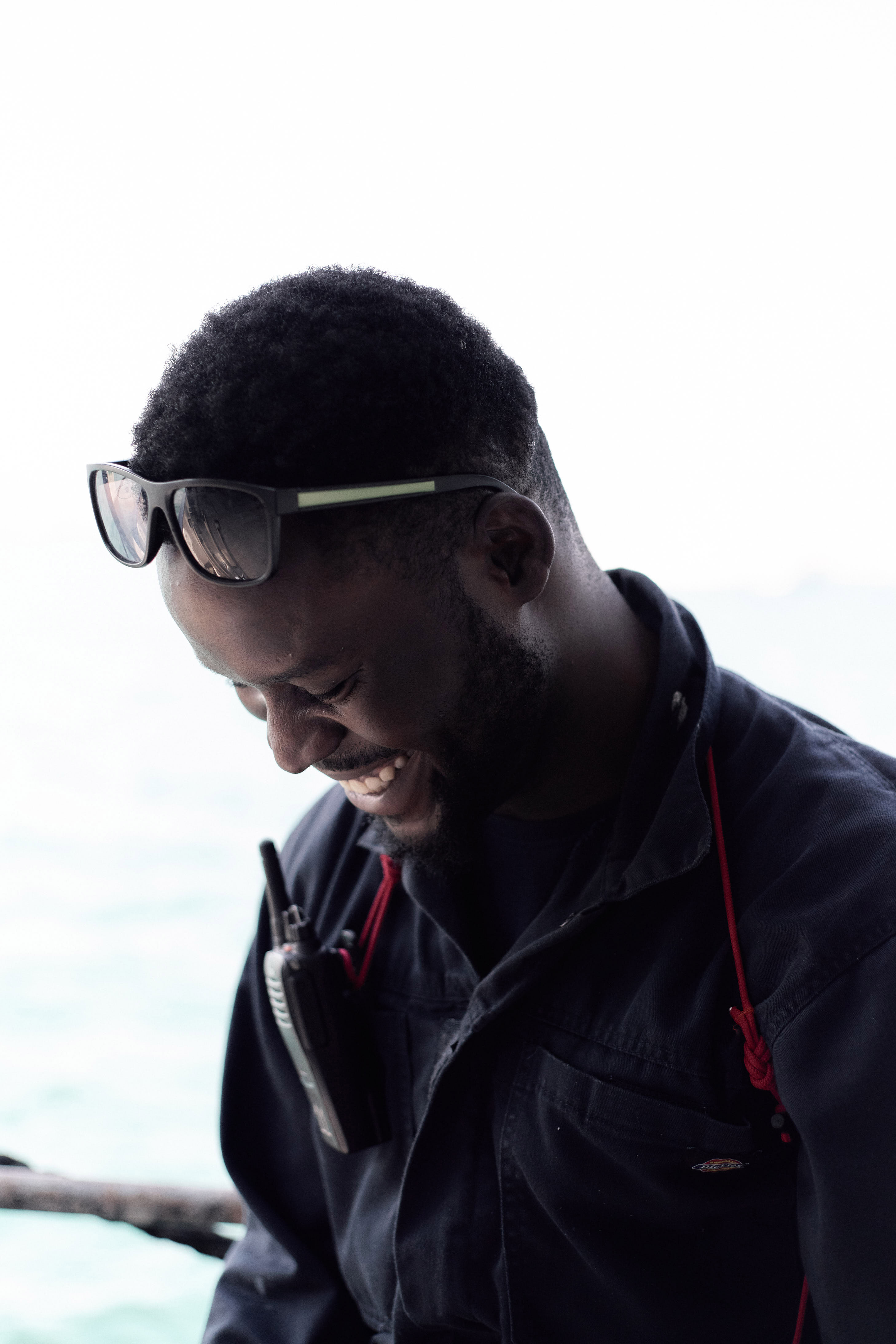 Portrait shot of a crew member with sunglasses on their head looking down and smiling