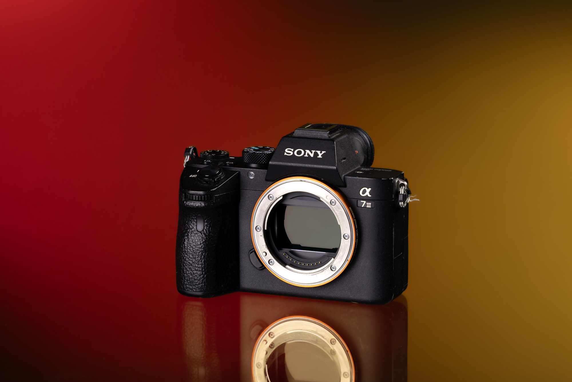 Gear shot of Sony A7 III in front of red and yellow background with reflection