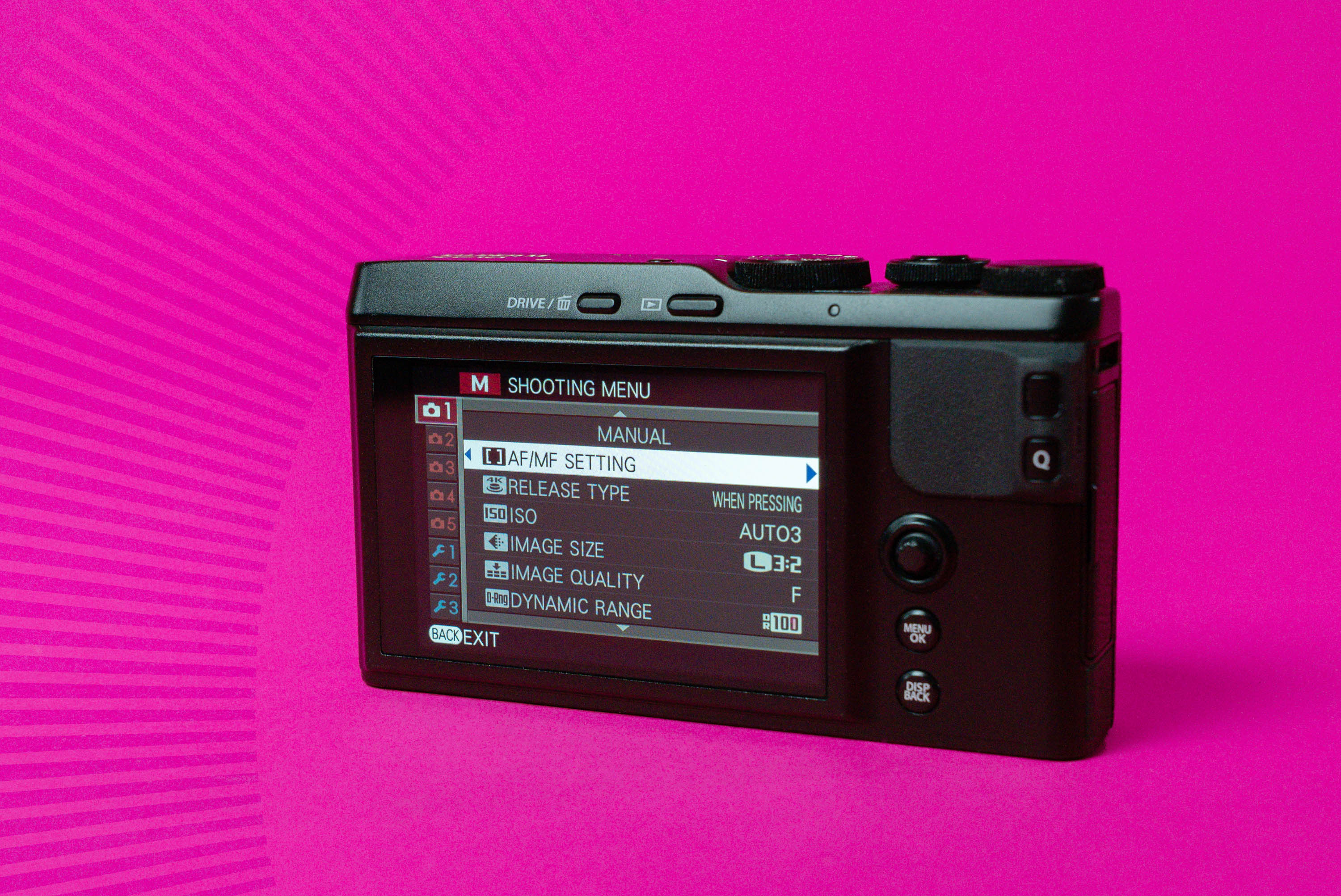 Backside of a Fujifilm XF10 showing the menu on the LCD screen on a pink background