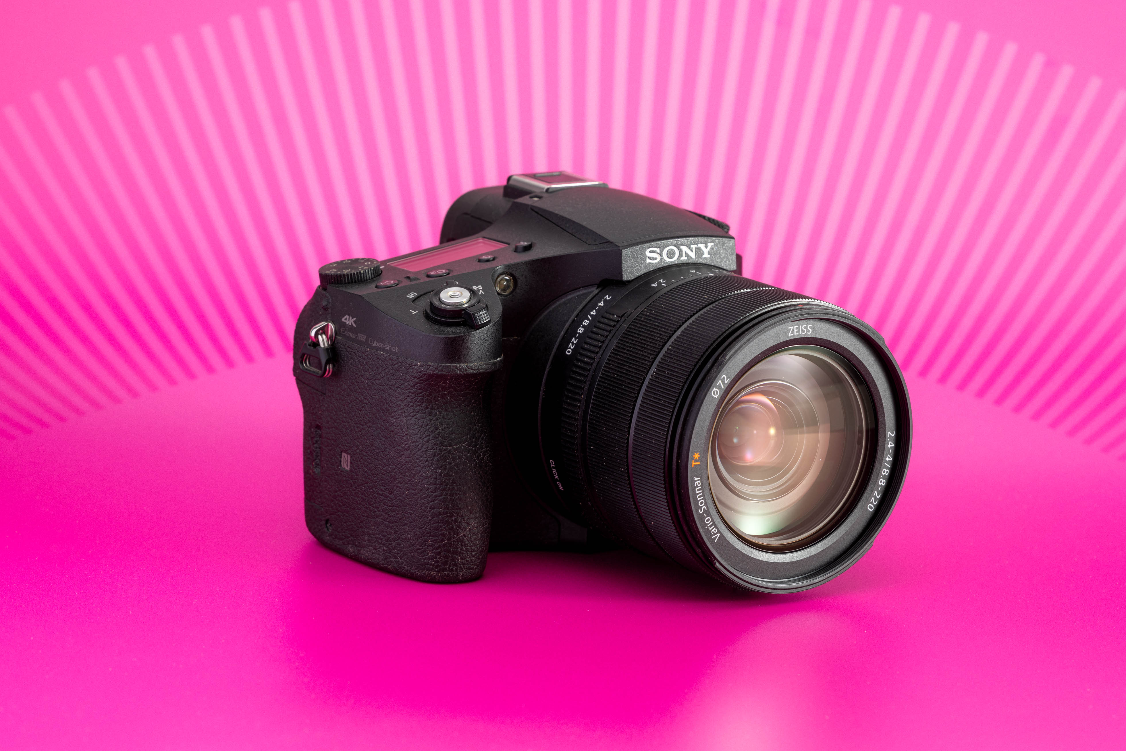 Sony RX10 IV fotografiada sobre fondo rosa, con objetivo zoom integrado. Foto de Connor Redmond