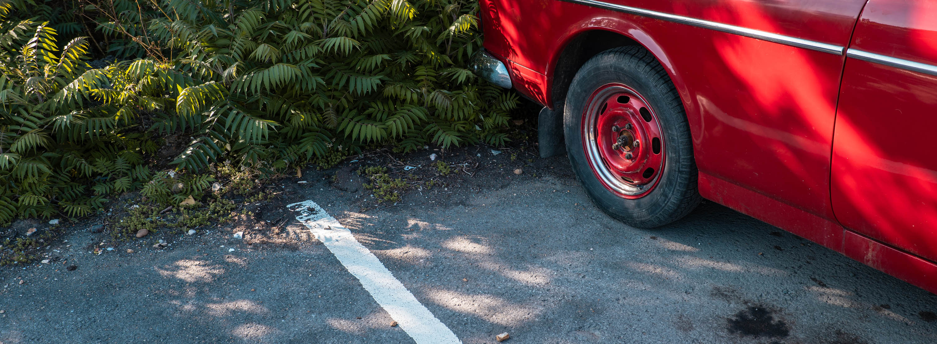 A panoramic cropped image of a red parked car, photo by Jakub Golis with a Panasonic S5