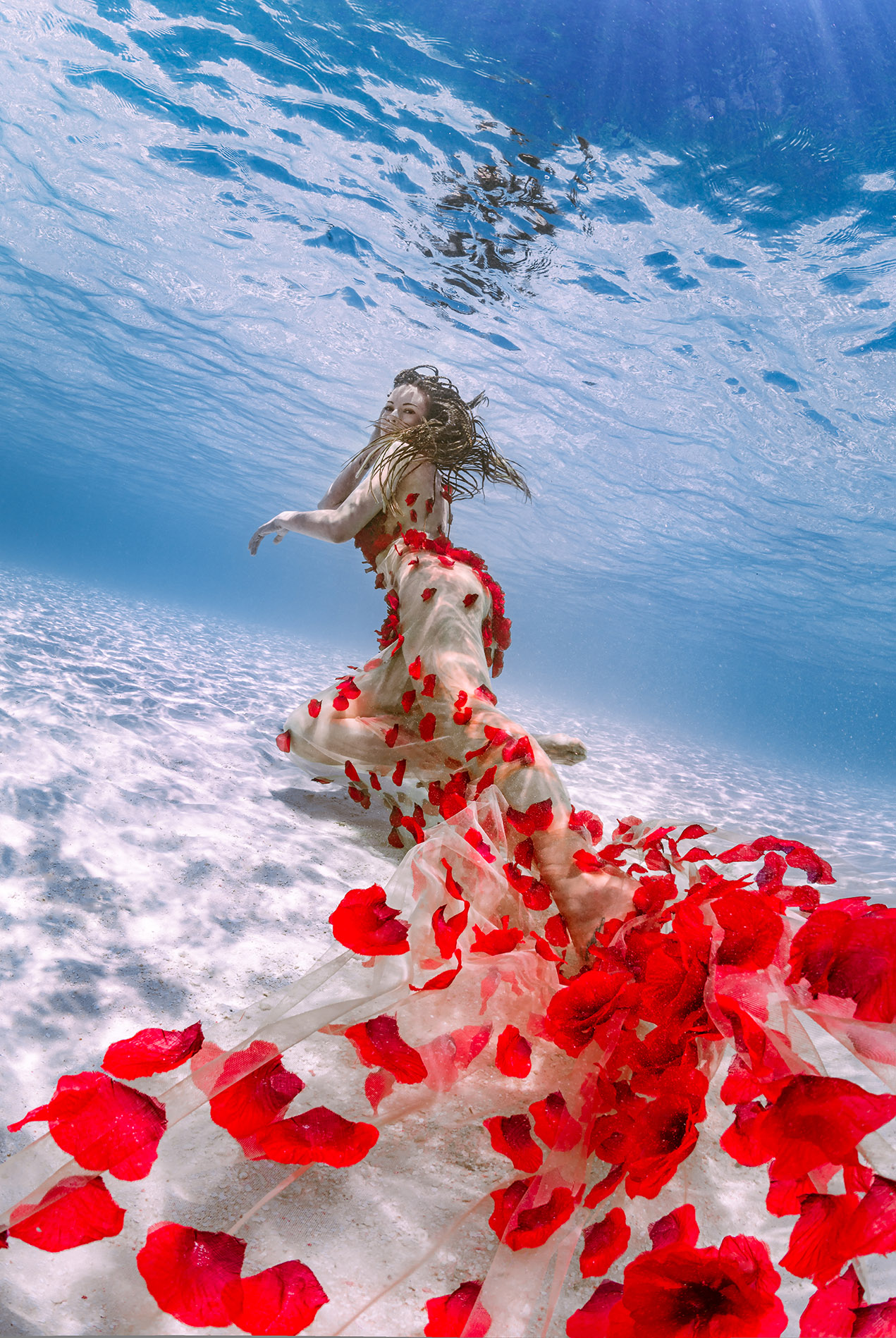 Unterwasserbild von einer Frau mit einem blumenbestickten Klei