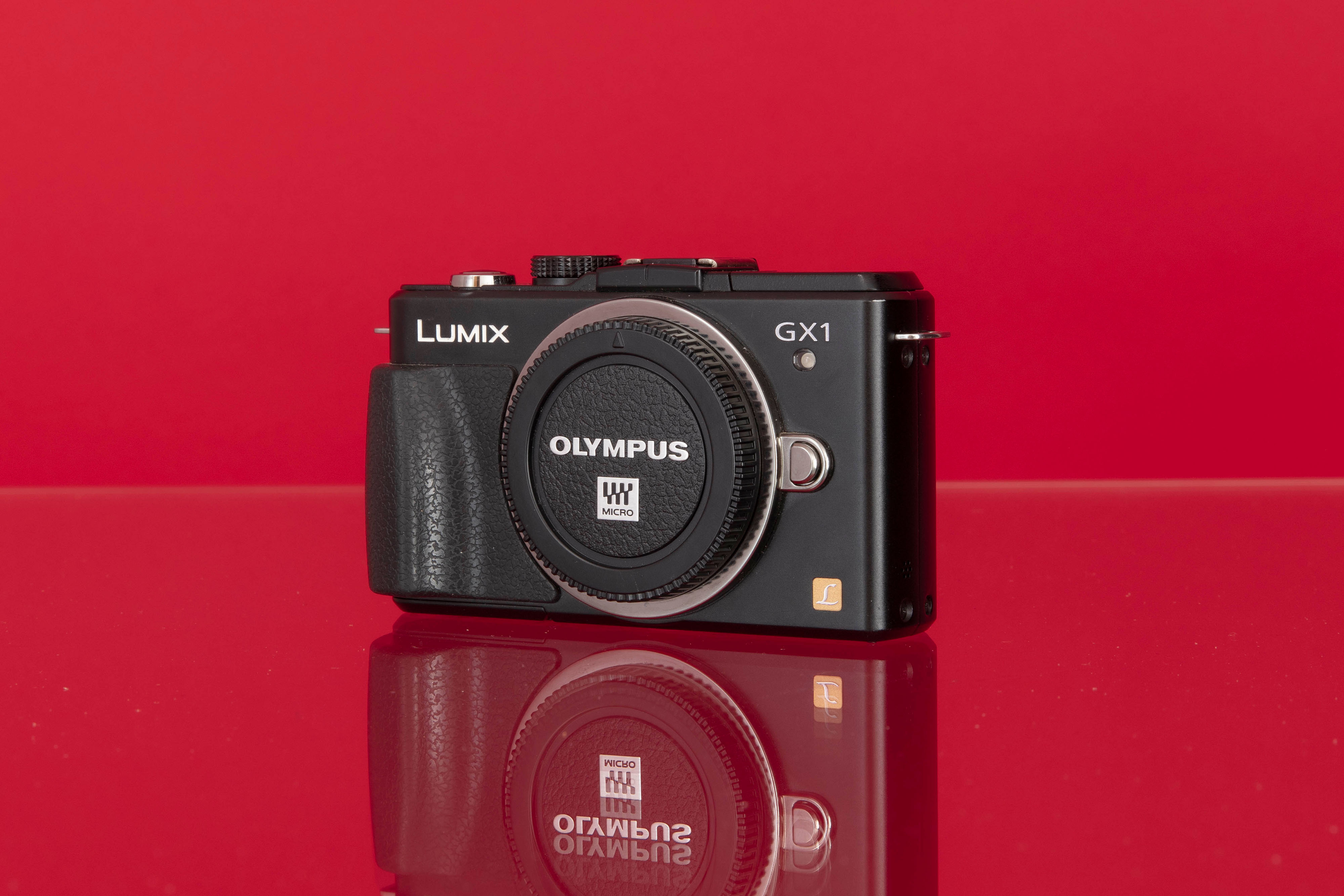 Gebrauchte Panasonic DMC-GX1 auf rotem Hintergrund.