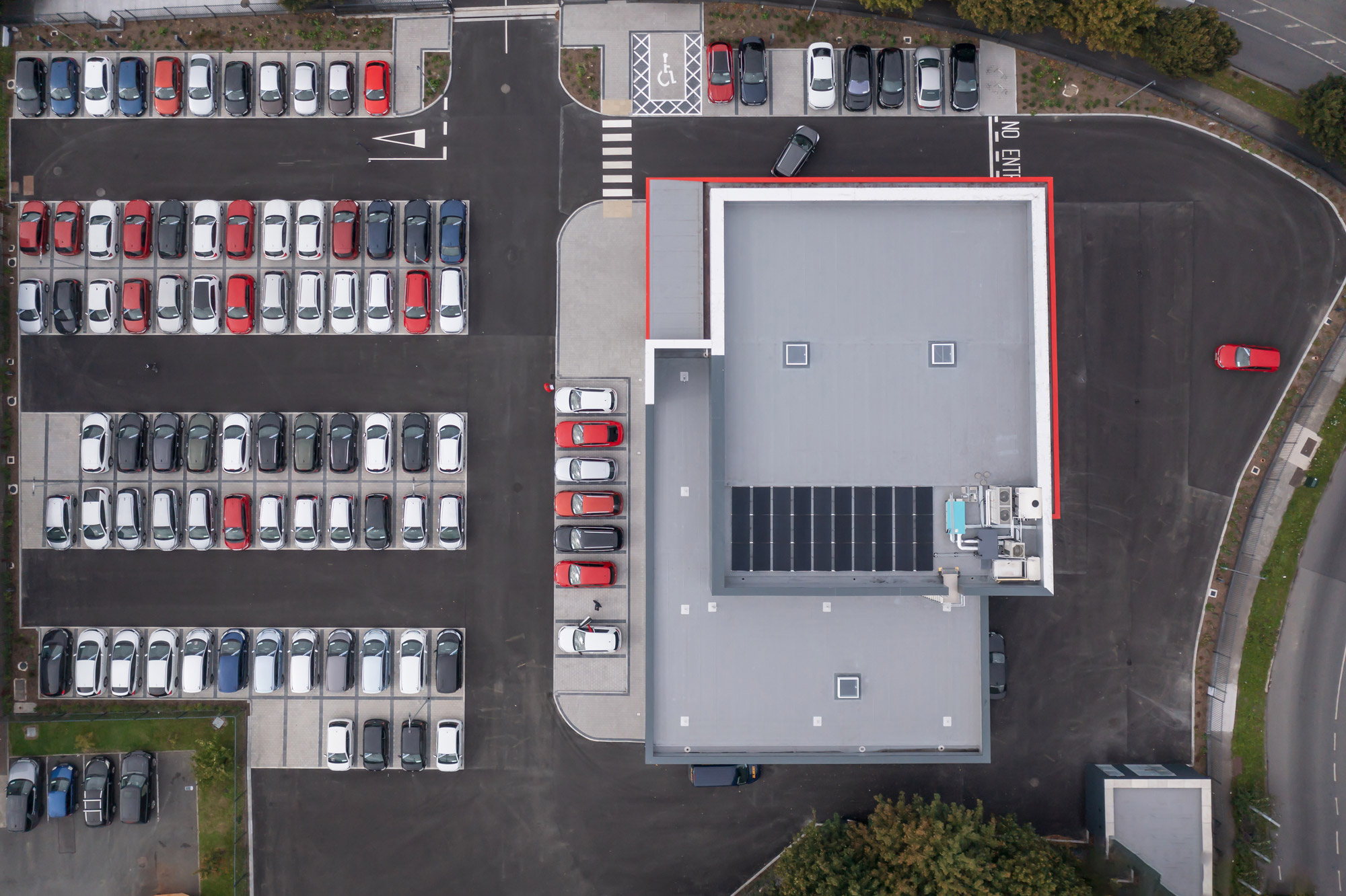 Het dak van een gebouw met een parkeerplaats vol auto's erbuiten. Geschoten door Paul Moore met de DJI Mavic 2 Pro.