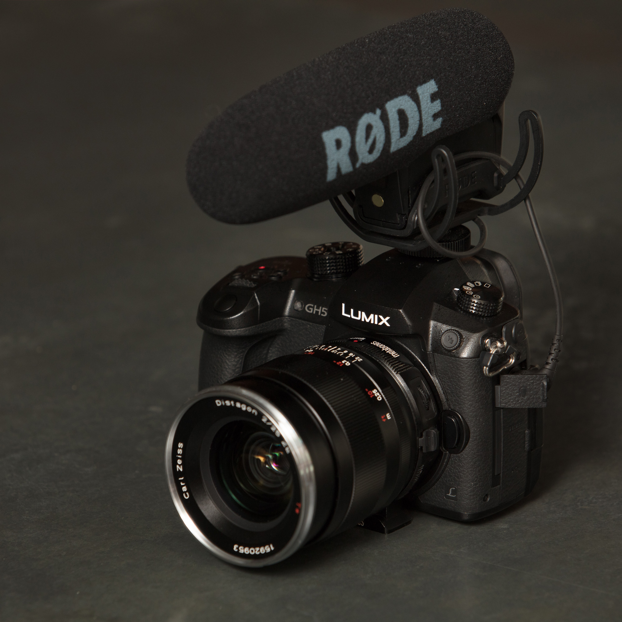 Une photo du Panasonic LUMIX GH5 avec un microphone Rode attaché sur un fond gris.