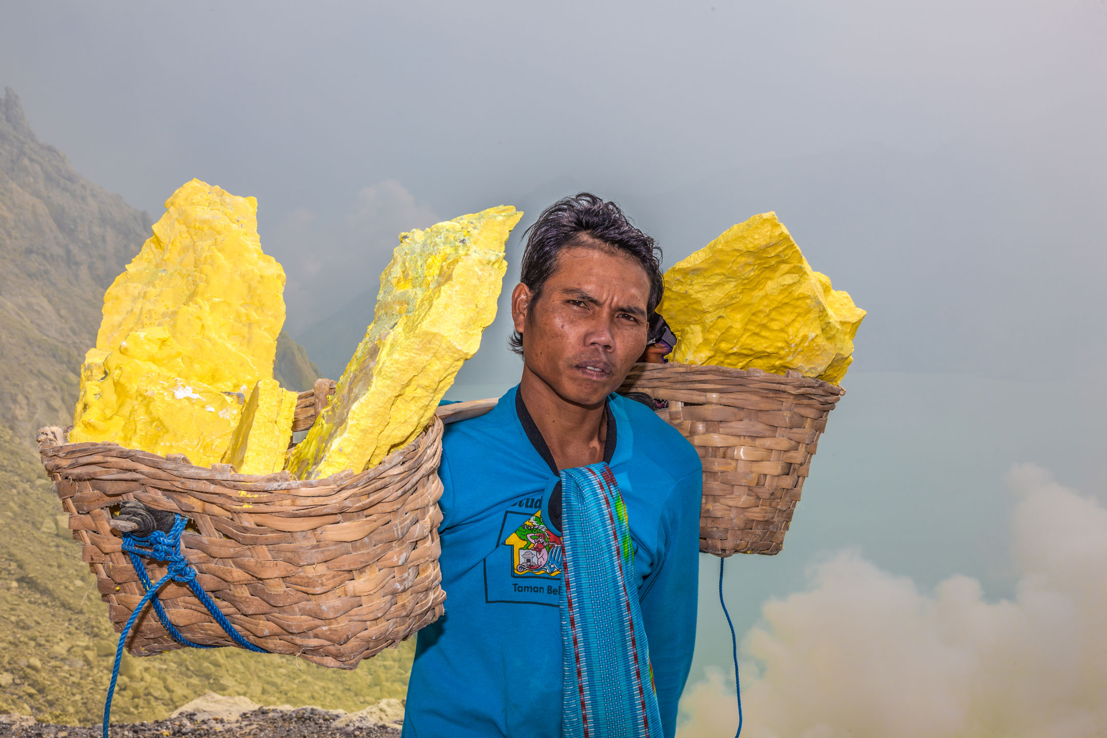 Arbeiter mit Körben voller Schwefel vor einer Mine im Inneren des Vulkans Ijen, Indonesien.