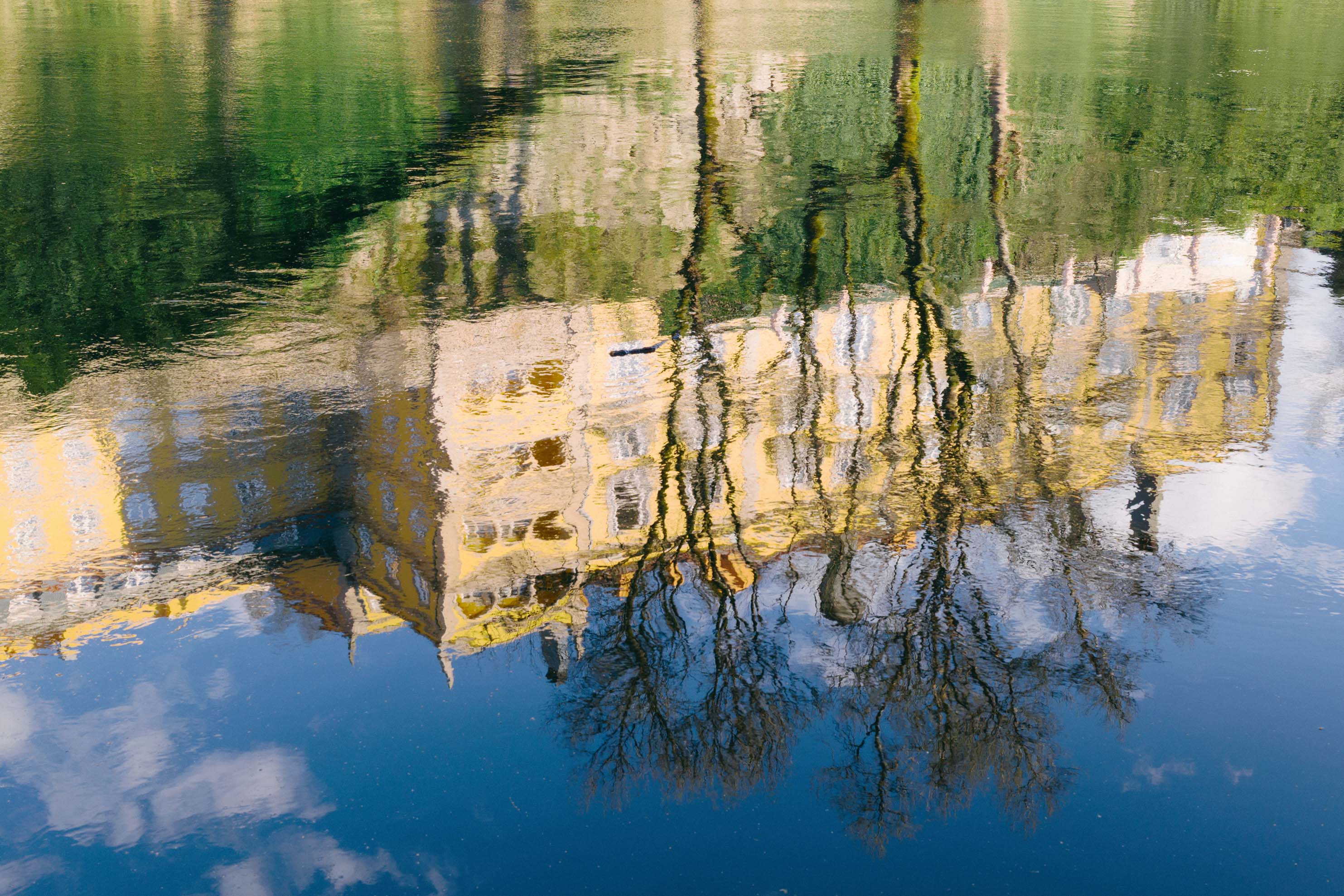 Bild eines großen gelben Gebäudes mit Bäumen, die sich im Wasser eines Flusses spiegeln. Aufgenommen von Connor Redmond mit der Sigma BF.
